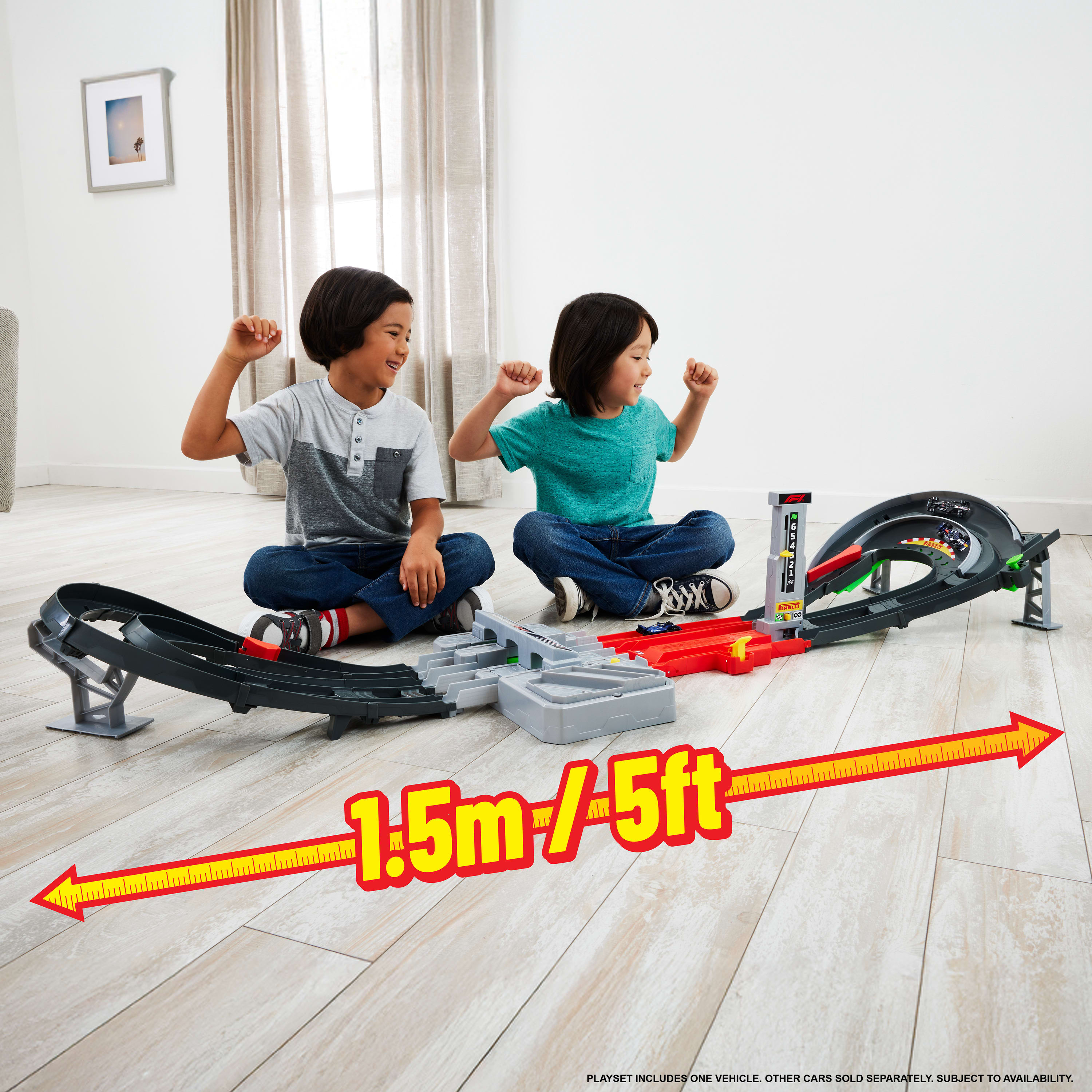 Dos niños sentados cerca de un juguete de pista de carreras. Una flecha roja muestra la longitud de 1,5 m de la pista.