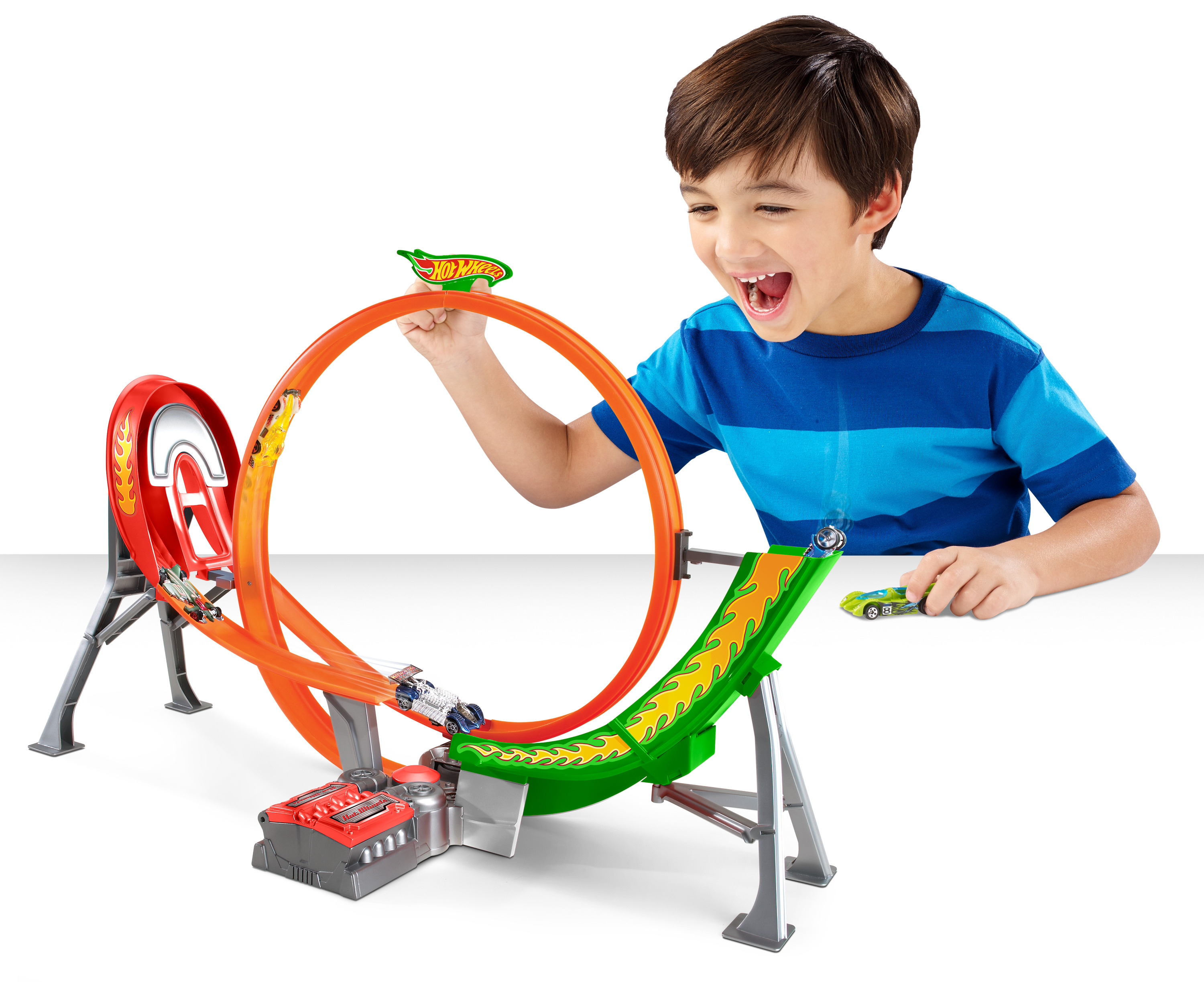 Chłopiec z ekscytacją bawi się torem Hot Wheels. Samochody ścigają się przez pętle. Tor jest pomarańczowy i zielony.