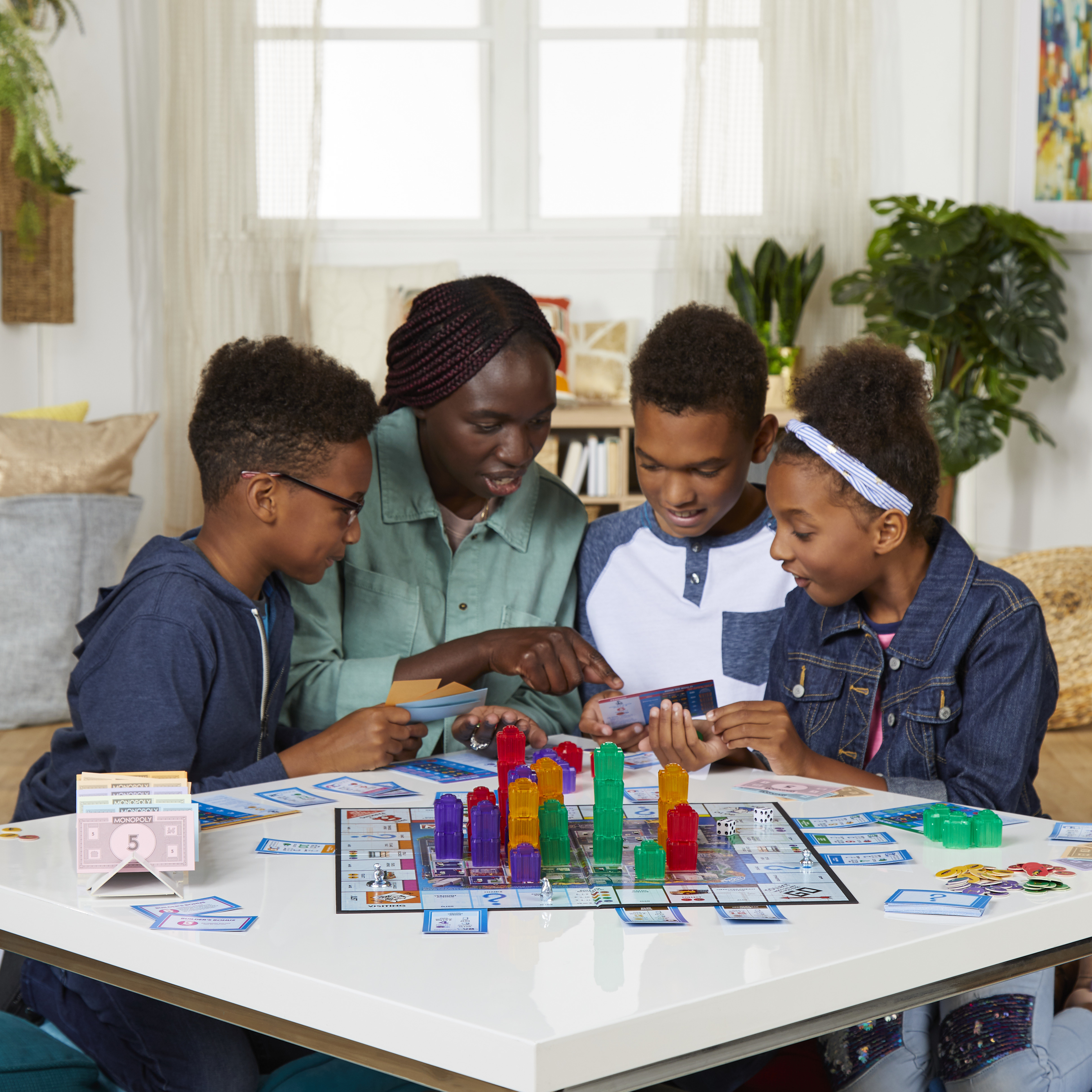 Gezin speelt Monopoly, bordspel op een witte tafel. Kinderen en een volwassene zijn gefocust op het spel.