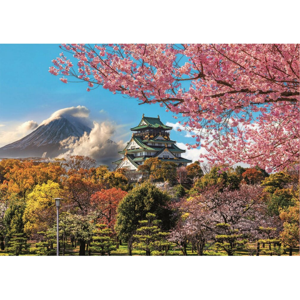 Castillo japonés rodeado de árboles coloridos y flores de cerezo. Una montaña nevada en el fondo bajo un cielo azul.
