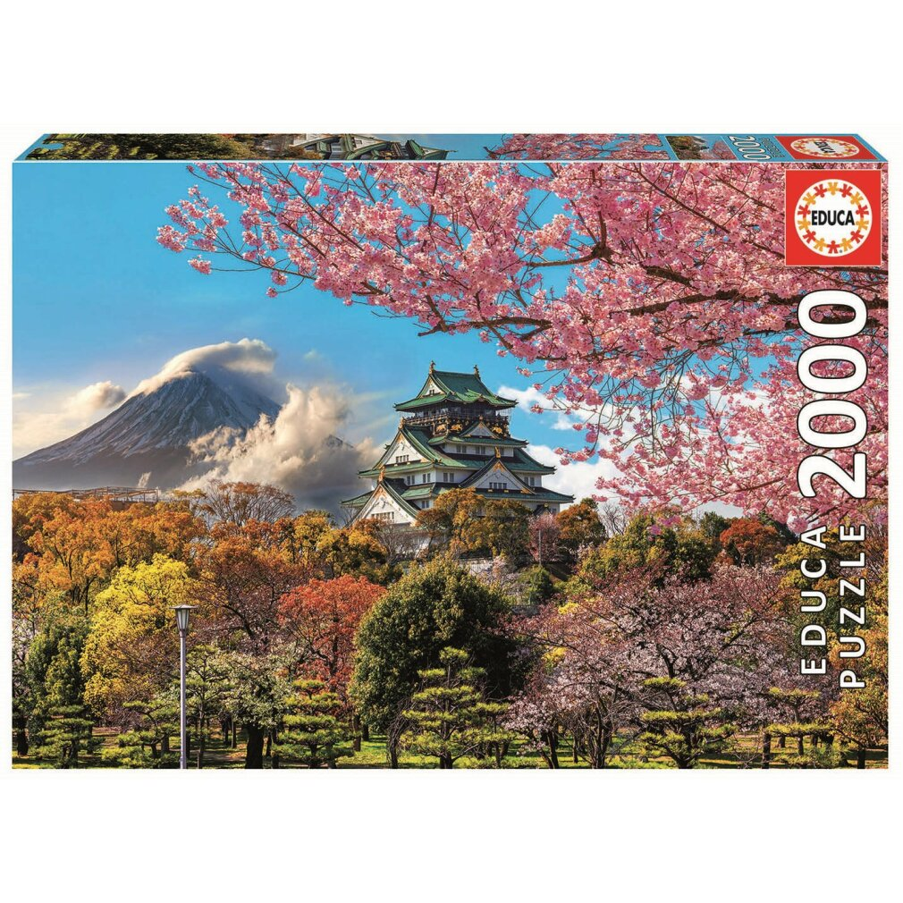 Una caja de rompecabezas muestra un castillo japonés rodeado de cerezos en flor, árboles y una montaña al fondo.