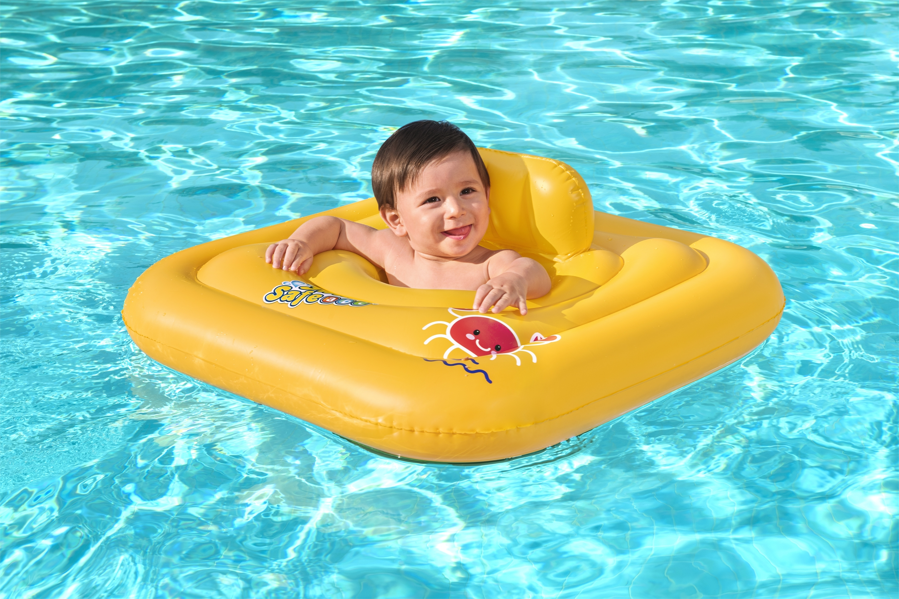 Ein Baby in einem gelben aufblasbaren Ring lächelt in einem blauen Pool. Der Ring hat ein Krabbendesign.
