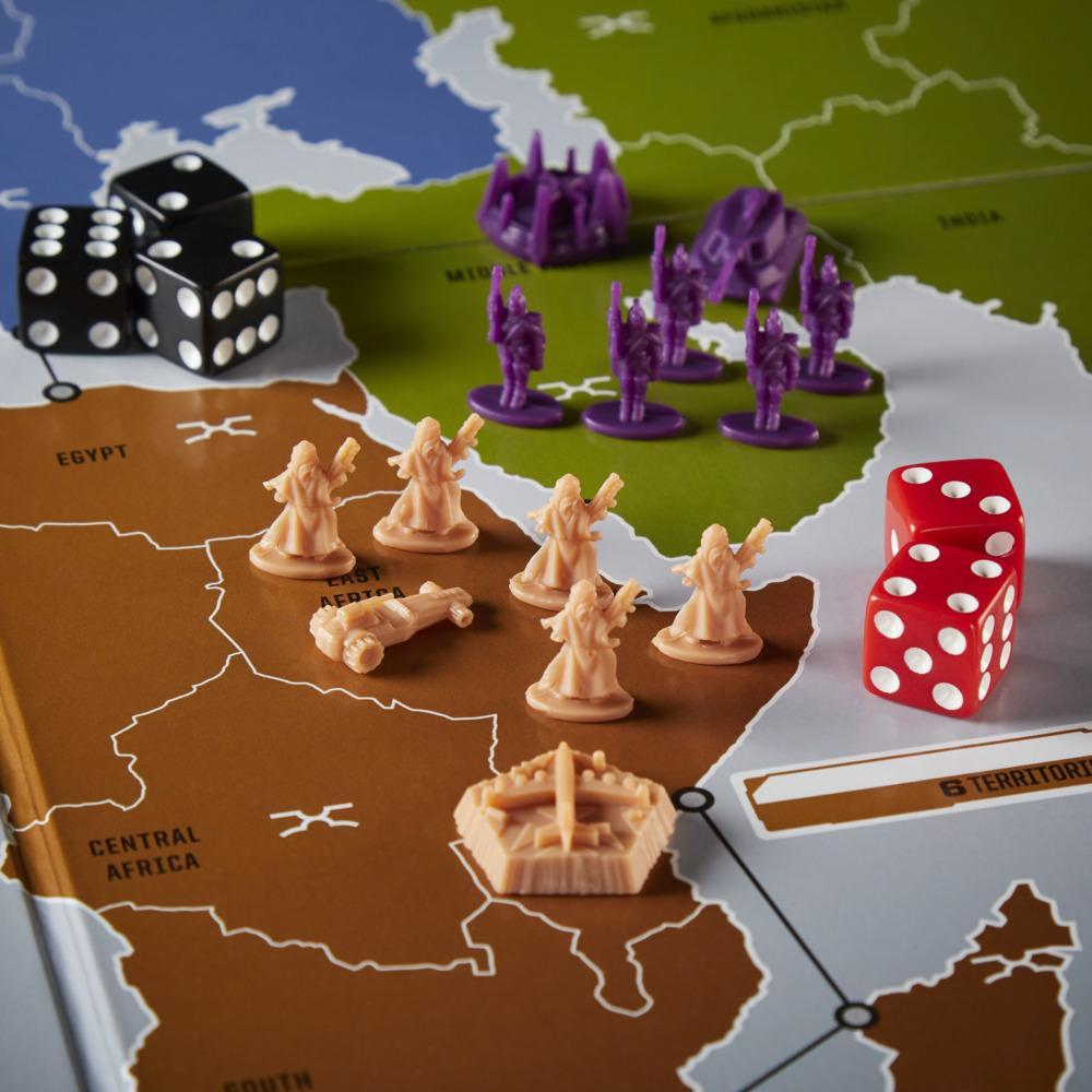 Un juego de mesa con dados y piezas en un mapa. Hay dados negros y rojos, y piezas de juego beige y moradas.