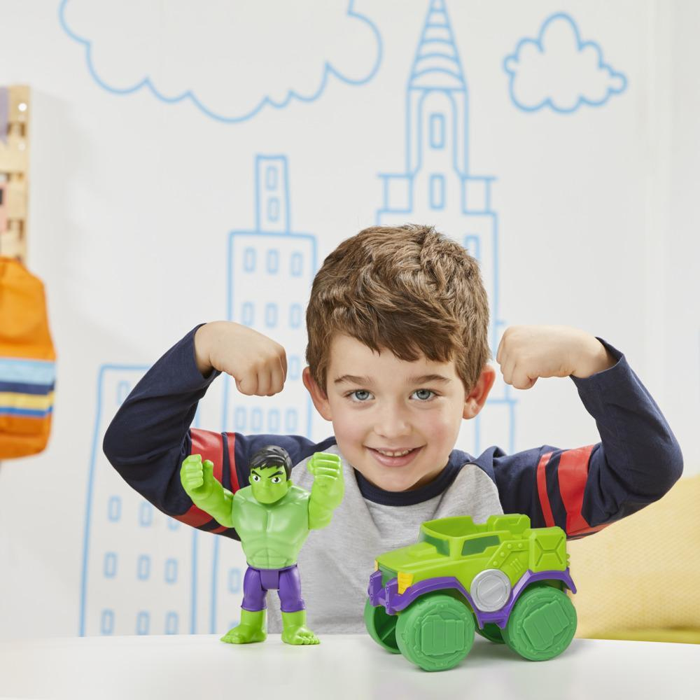 Ein Junge beugt seine Arme. Hulk-Figur und grünes Autosspielzeug davor. Weißer Hintergrund mit blauen Zeichnungen.