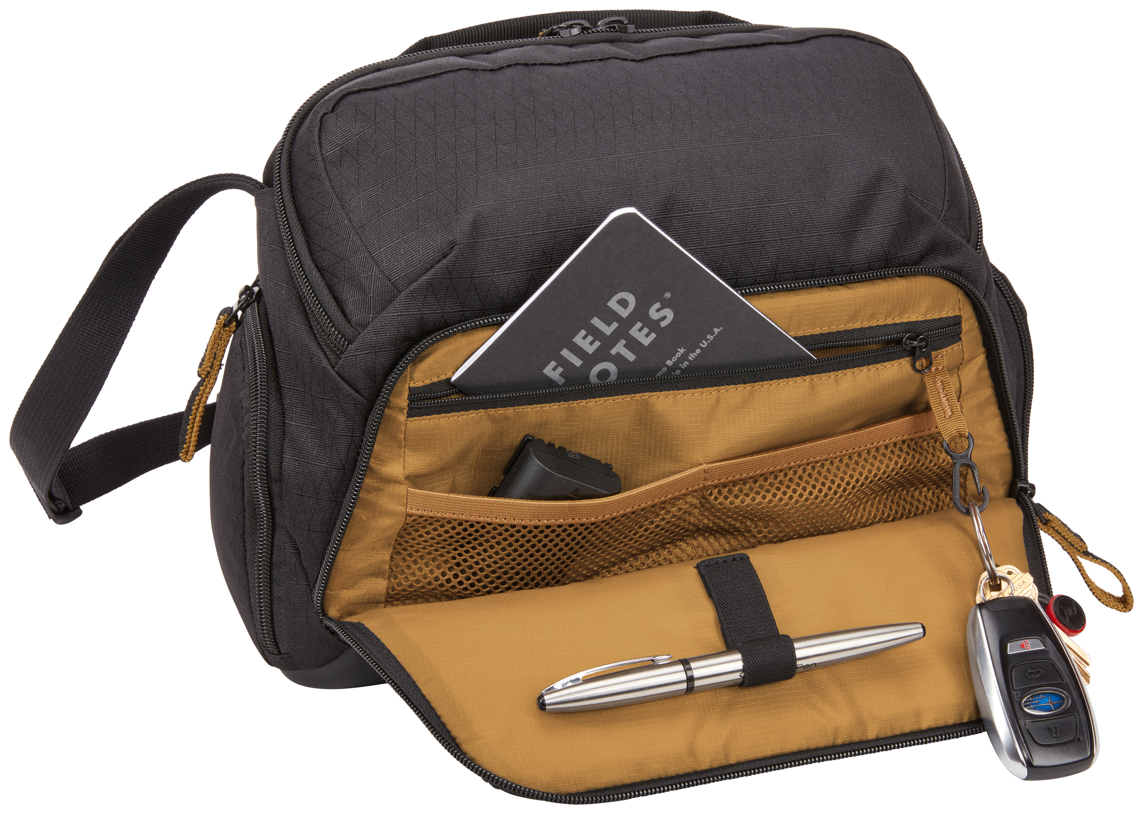 Schwarze Tasche mit offenen Fächern. Innen befinden sich ein Notizbuch, ein Stift, Schlüssel und ein kleines schwarzes Objekt.