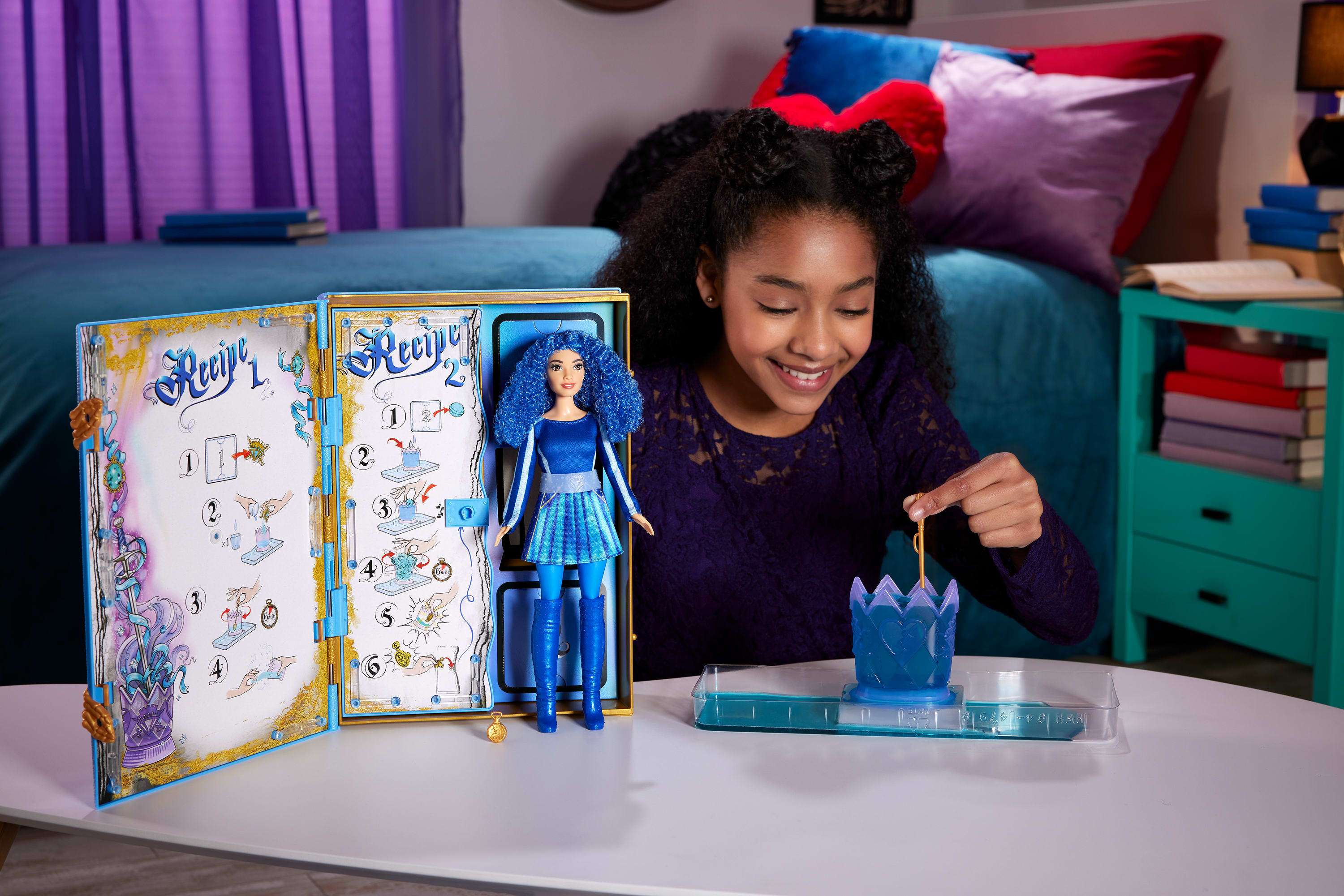 Dziewczyna uśmiecha się podczas zabawy zestawem dla lalek. Widoczna jest lalka i instrukcje. W tle łóżko i szafka nocna.