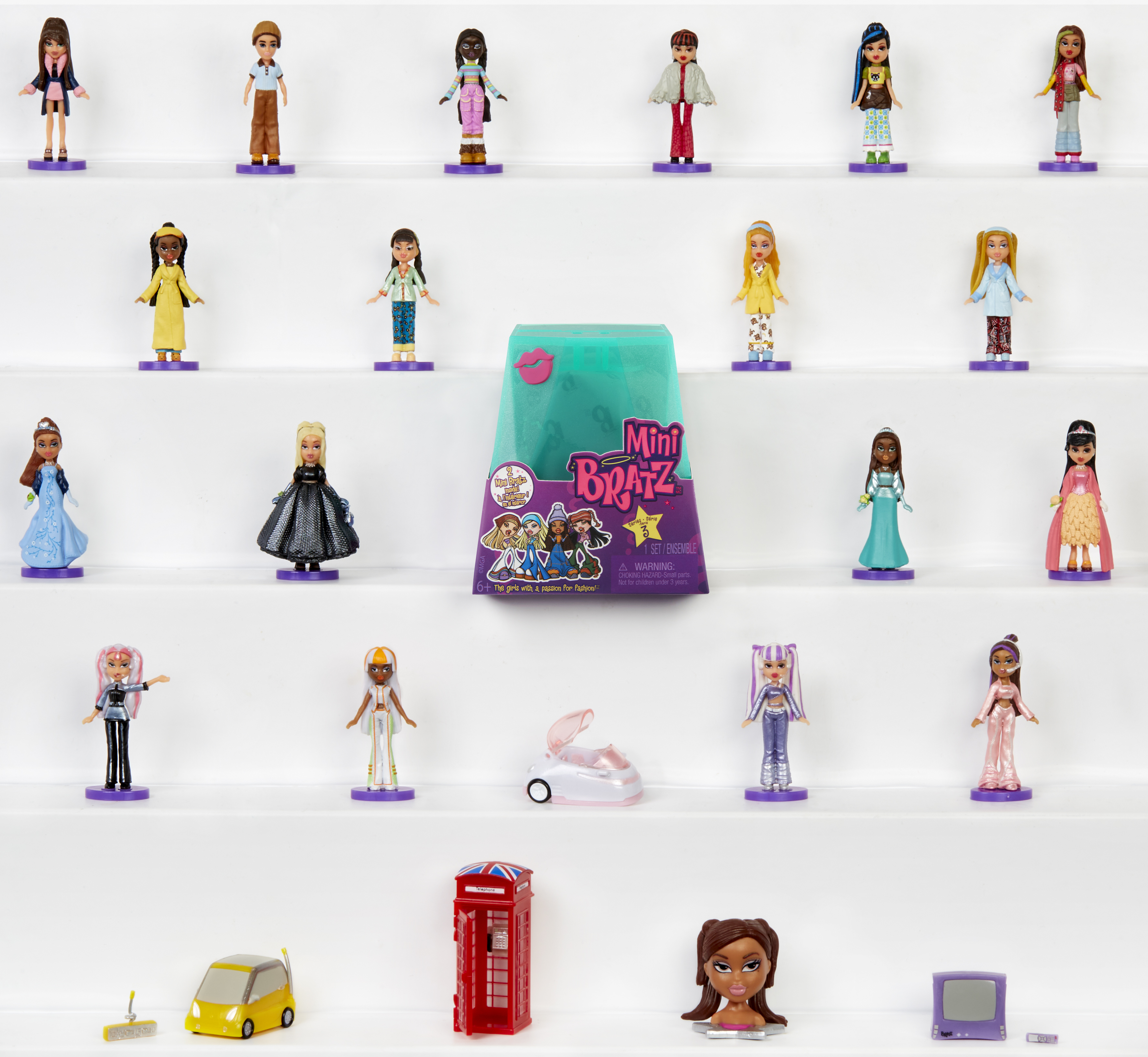 Obraz przedstawia ekspozycję lalek Bratz Mini, zabawkowe auto i czerwoną budkę telefoniczną na półkach.