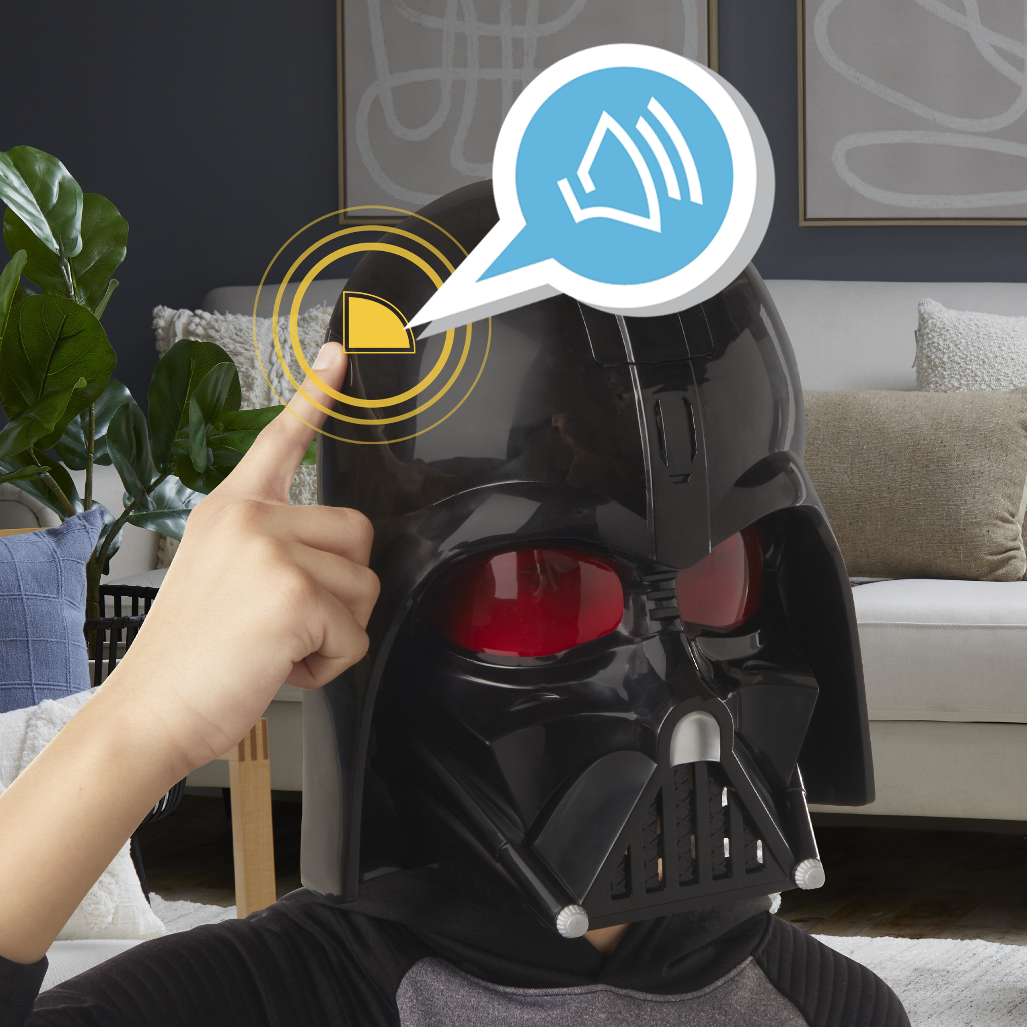 Una persona con una máscara de Darth Vader toca un botón. Una burbuja de diálogo con ondas de sonido está sobre la máscara.