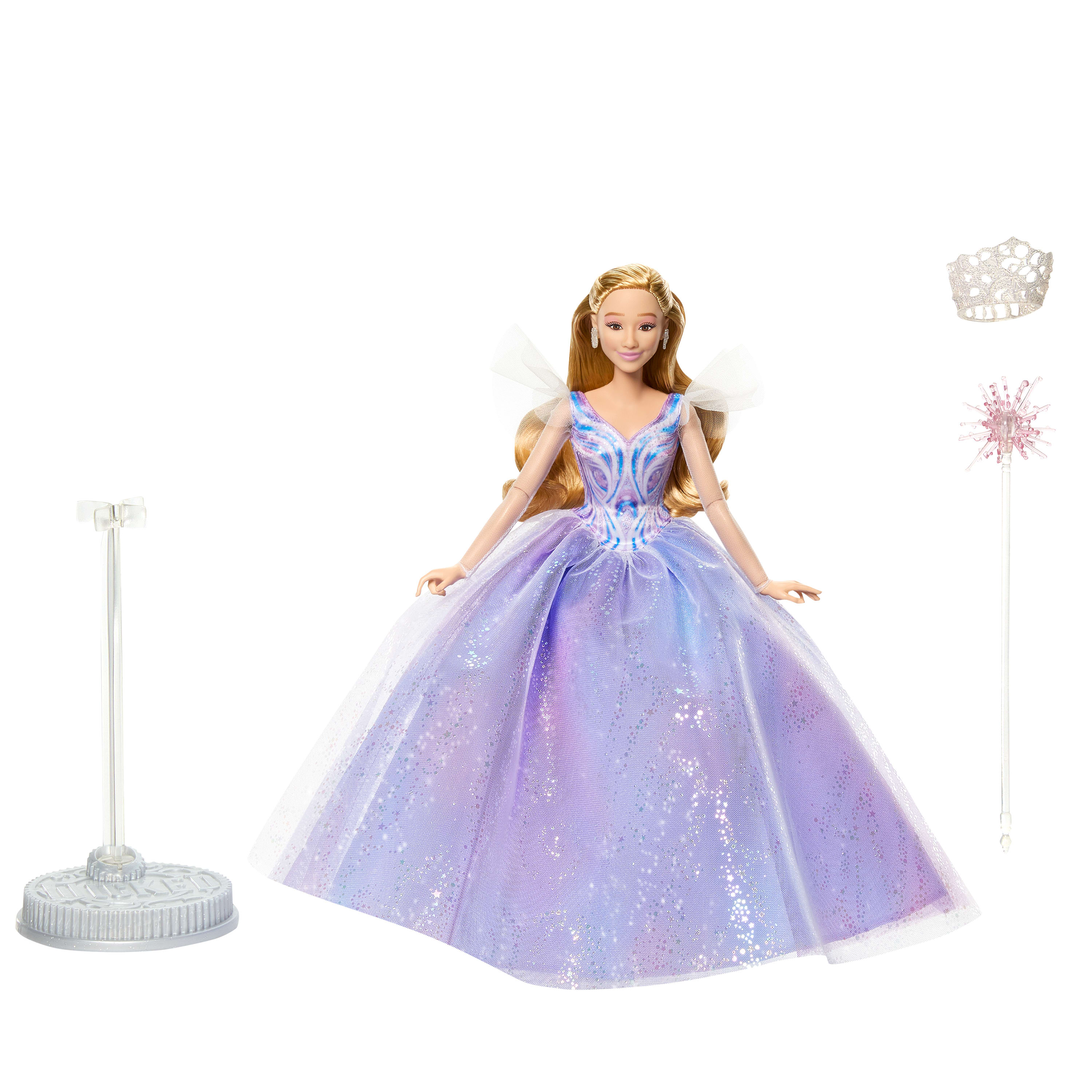 Eine Barbie-Puppe in einem lila Kleid mit Accessoires wie Krone und Zauberstab, steht vor weißem Hintergrund.