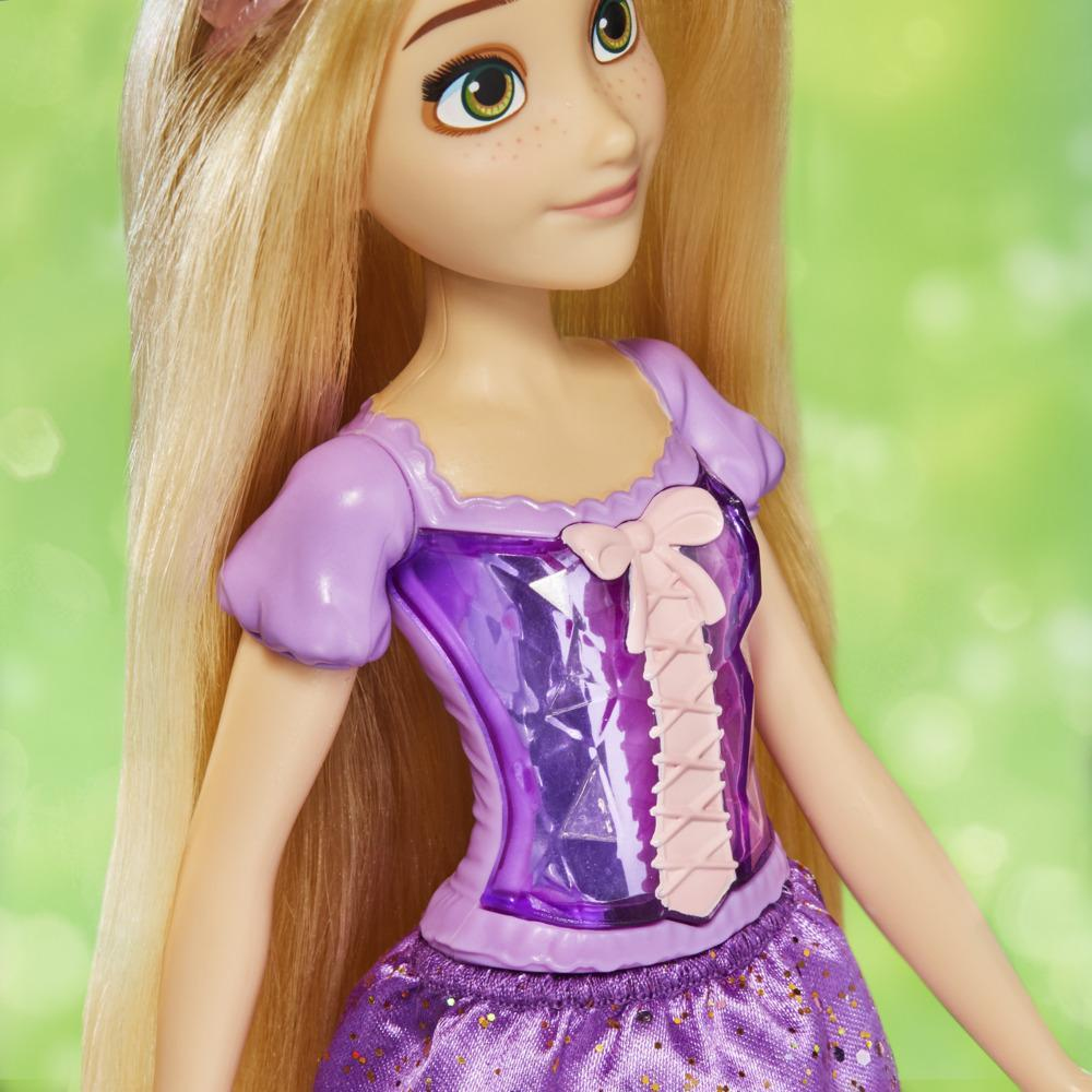 È mostrata una bambola di Rapunzel. Ha lunghi capelli biondi, occhi verdi e indossa un vestito viola con un fiocco rosa. Lo sfondo è verde.