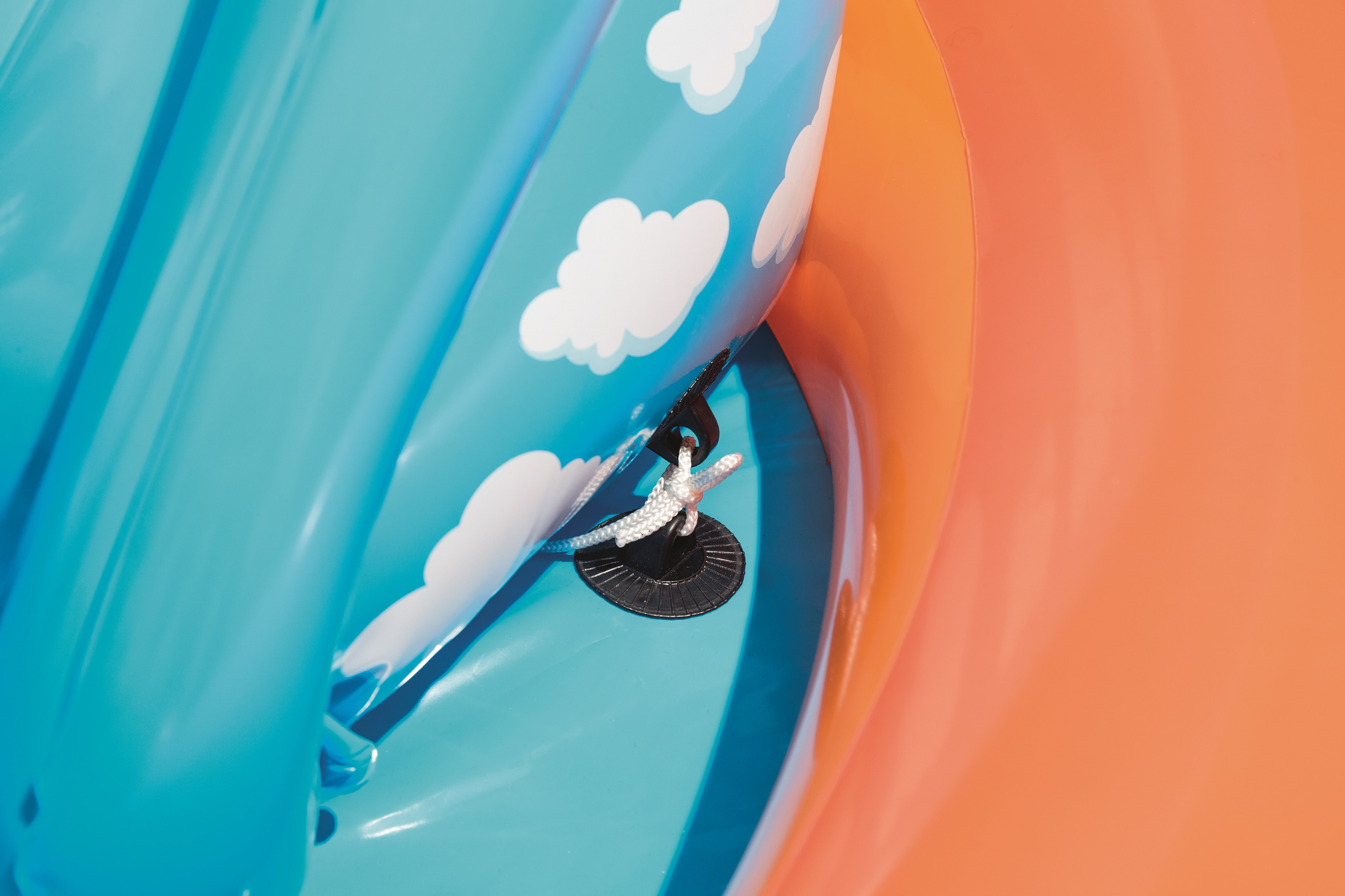 Zbliżenie niebieskiej dmuchanej zabawki z białymi chmurami, pomarańczowym tłem i detalami lin.