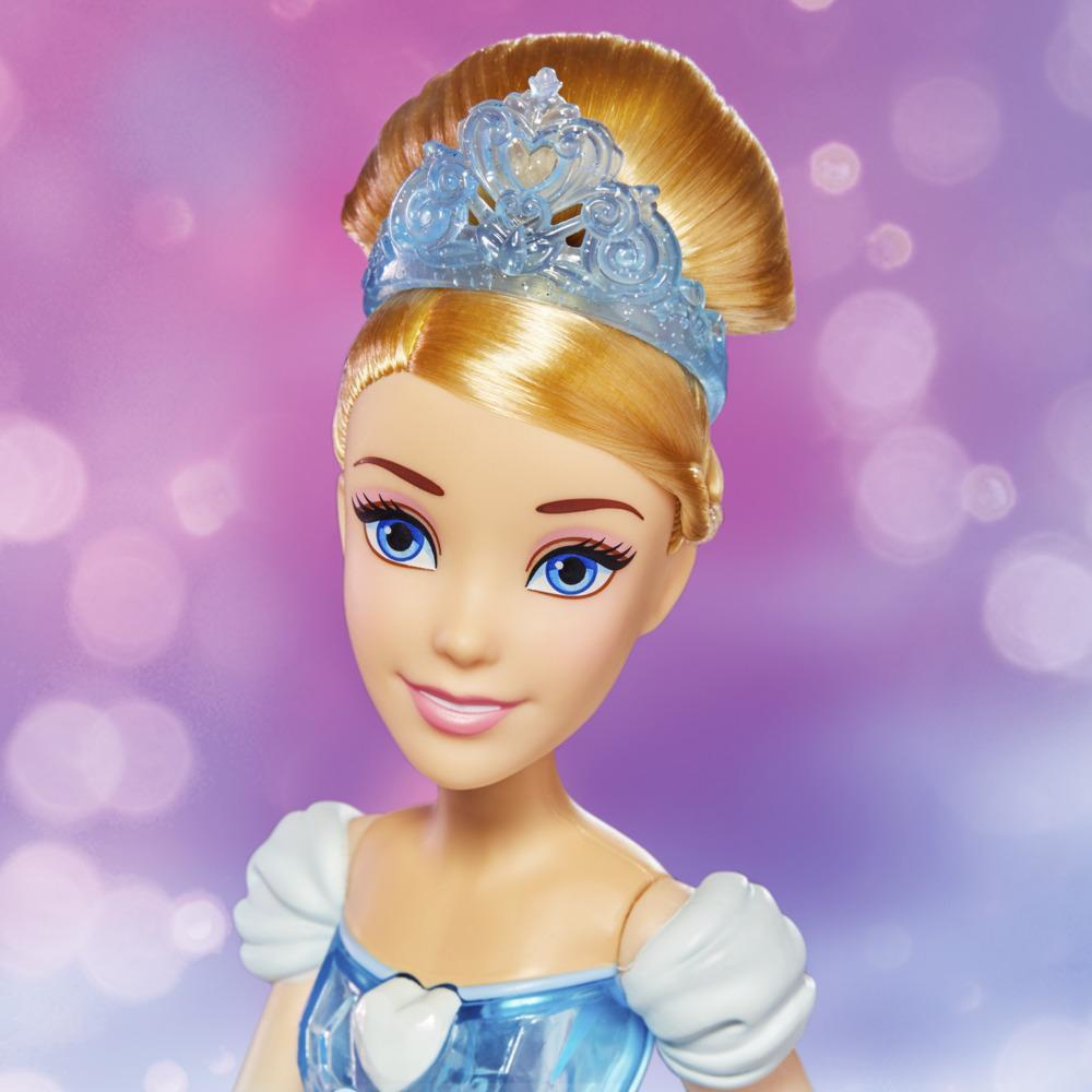 Muñeca de Cenicienta con cabello rubio, ojos azules y tiara. Viste un vestido azul con mangas blancas, sobre un fondo bokeh.