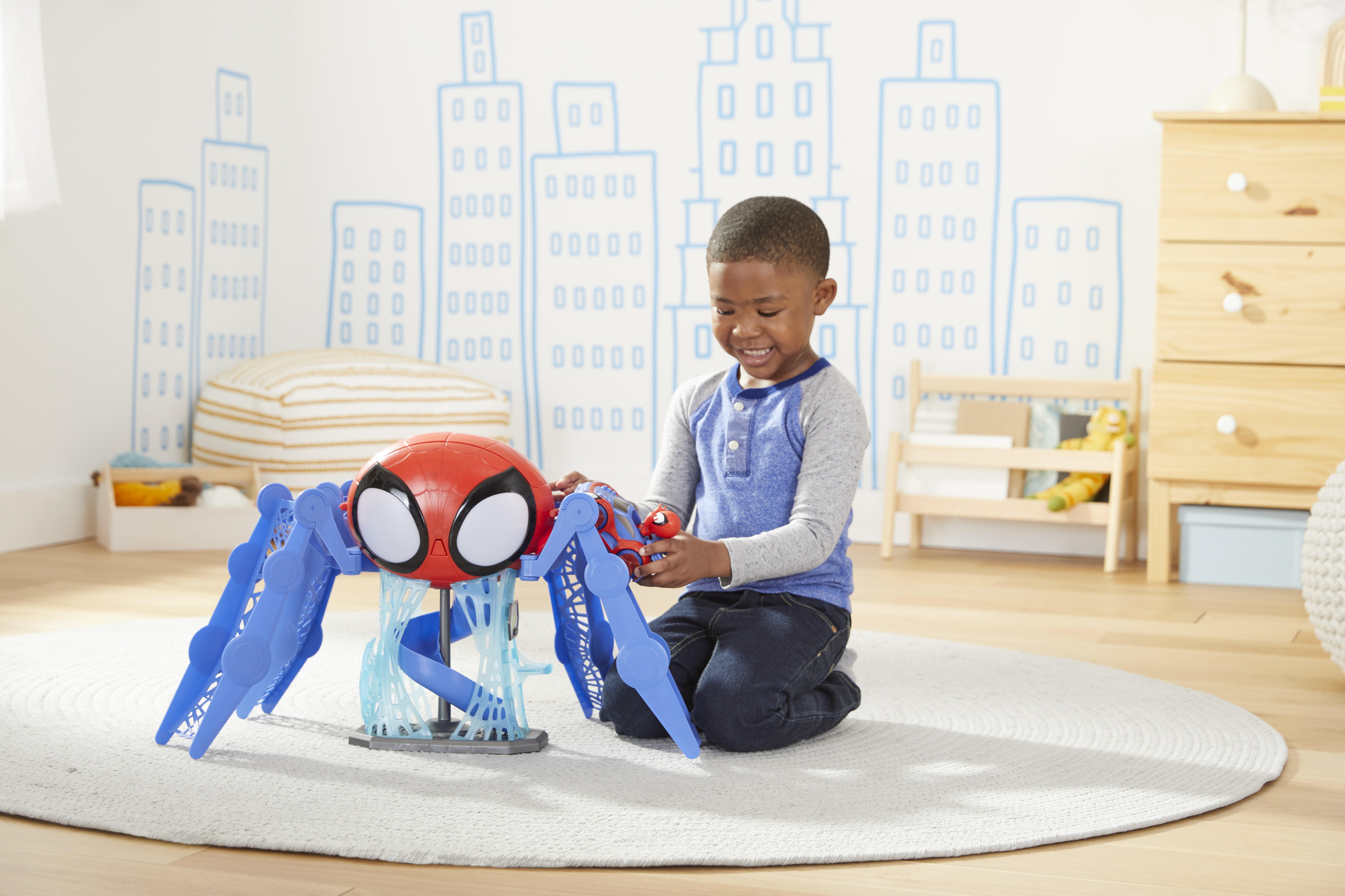 Un niño se arrodilla, jugando con un juguete de Spider-Man. El juguete es rojo y azul.
