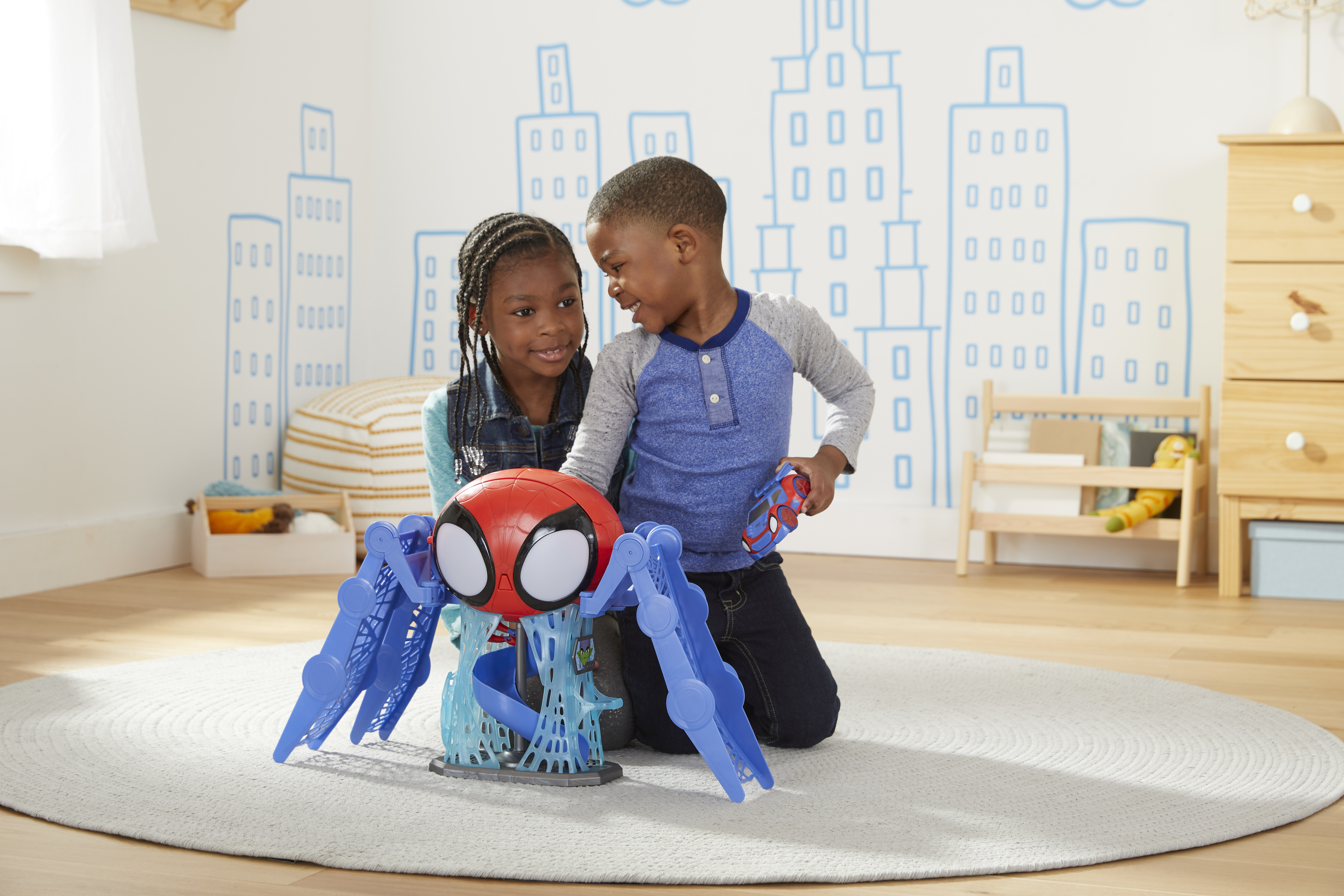 Dos niños juegan con un juguete de Spider-Man. El fondo tiene dibujos de un horizonte urbano.