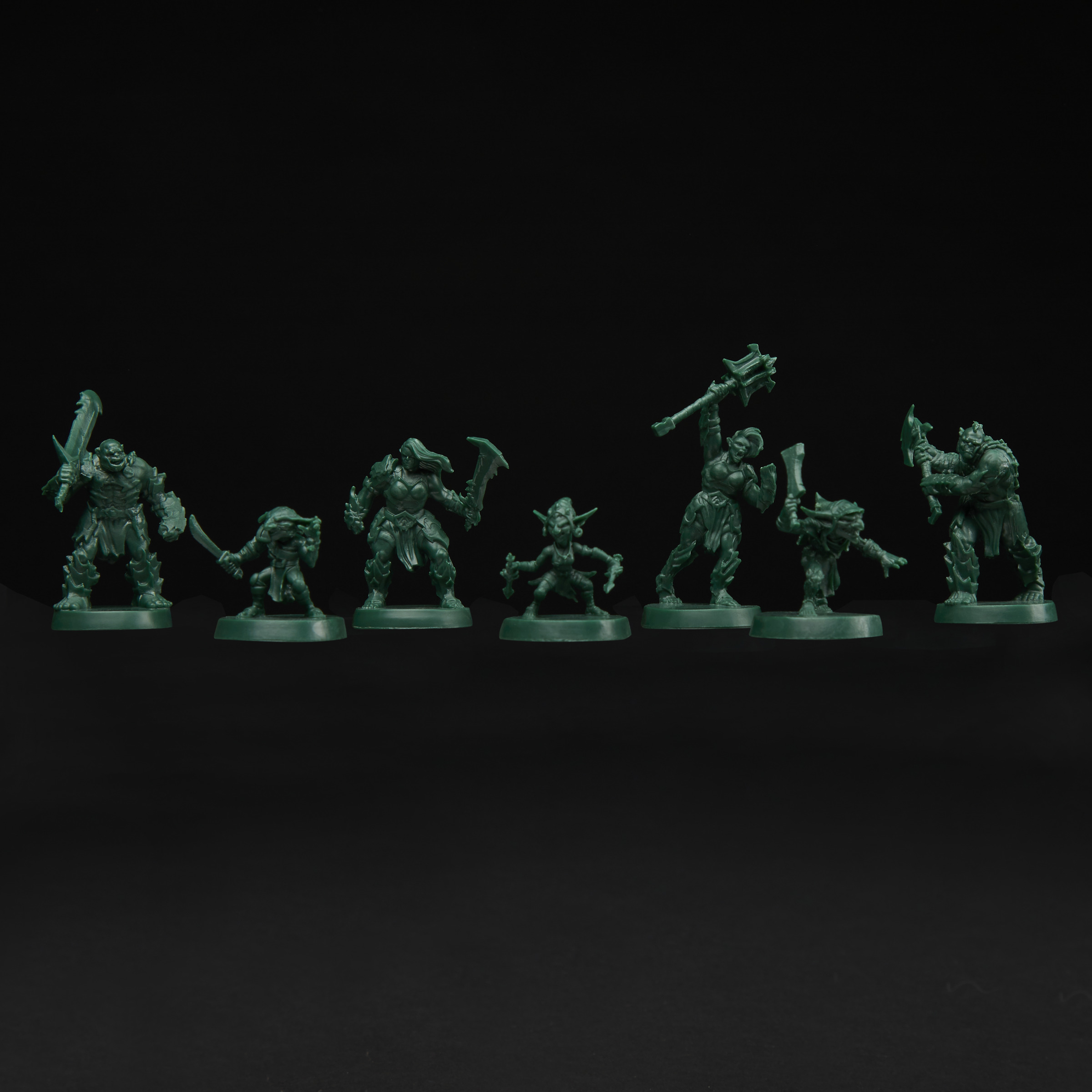 Figurine verdi di varie creature fantasy, tra cui orchi e goblin, disposte su sfondo nero.