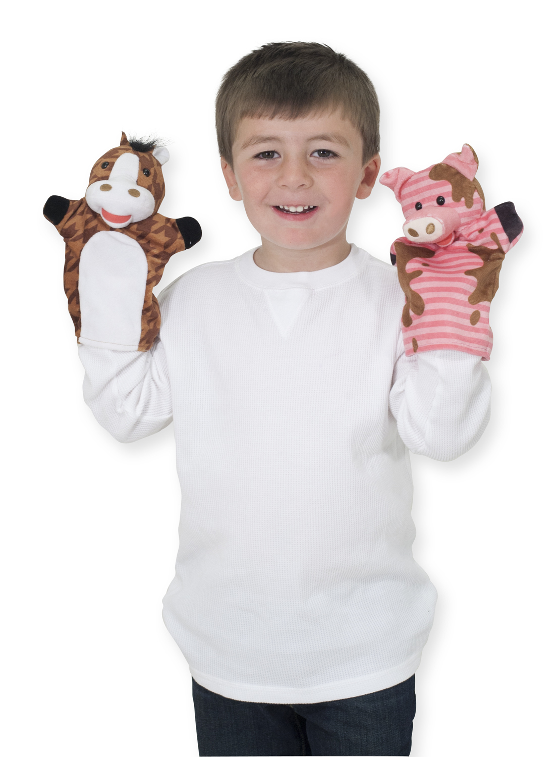 Ein Junge lächelt und hält Pferde- und Schweinehandpuppen. Er trägt ein weißes Hemd und blaue Jeans, isoliert auf weißem Hintergrund.