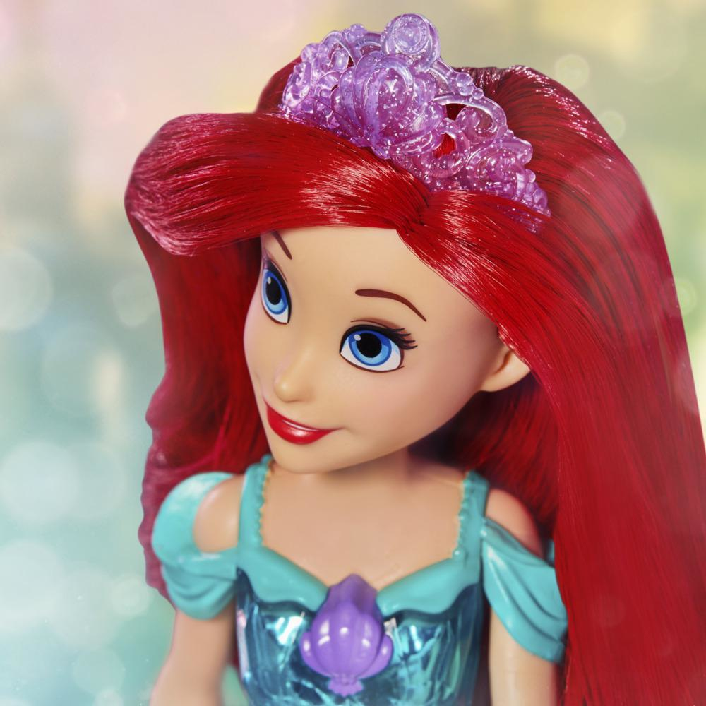 Bambola di Ariel con capelli rossi, occhi blu e una tiara viola. Indossa un vestito turchese. Lo sfondo è sfocato con colori chiari.