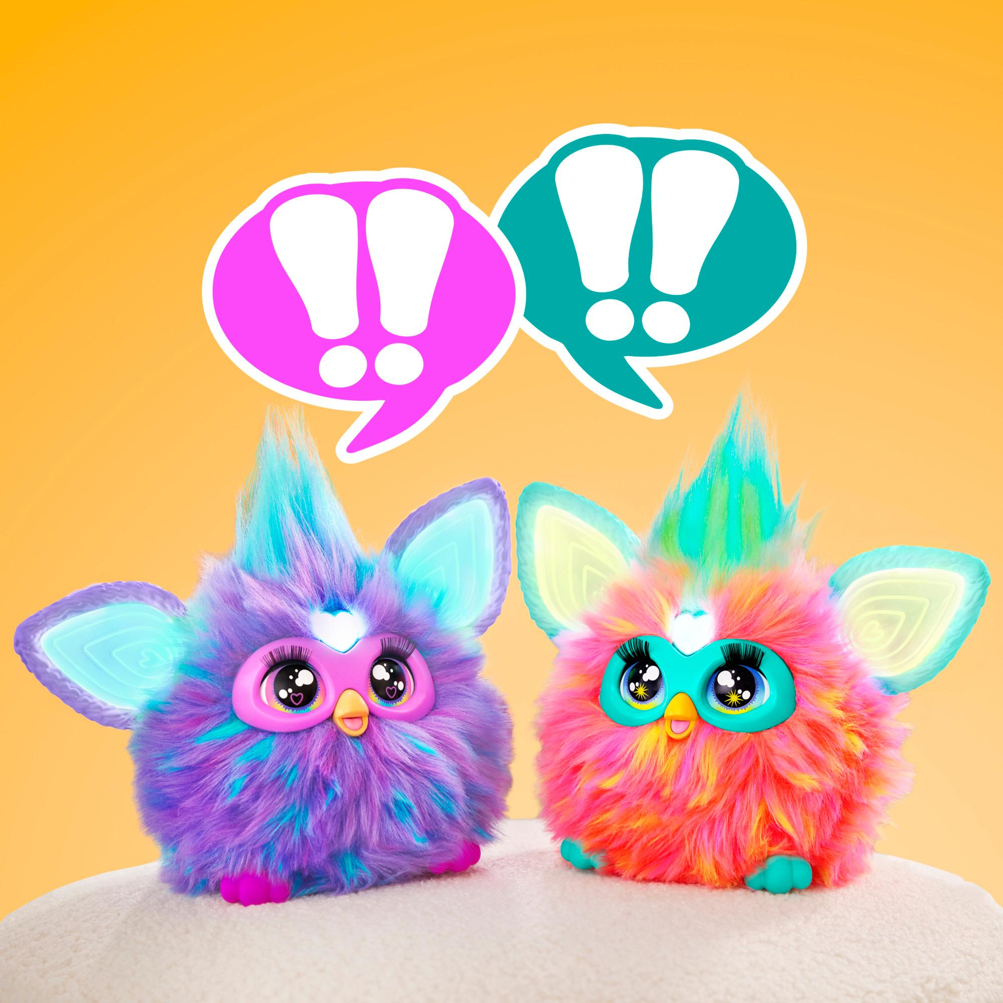 Zwei bunte Furby-Spielzeuge mit Sprechblasen. Eines ist lila, das andere rosa. Der Hintergrund ist orange.