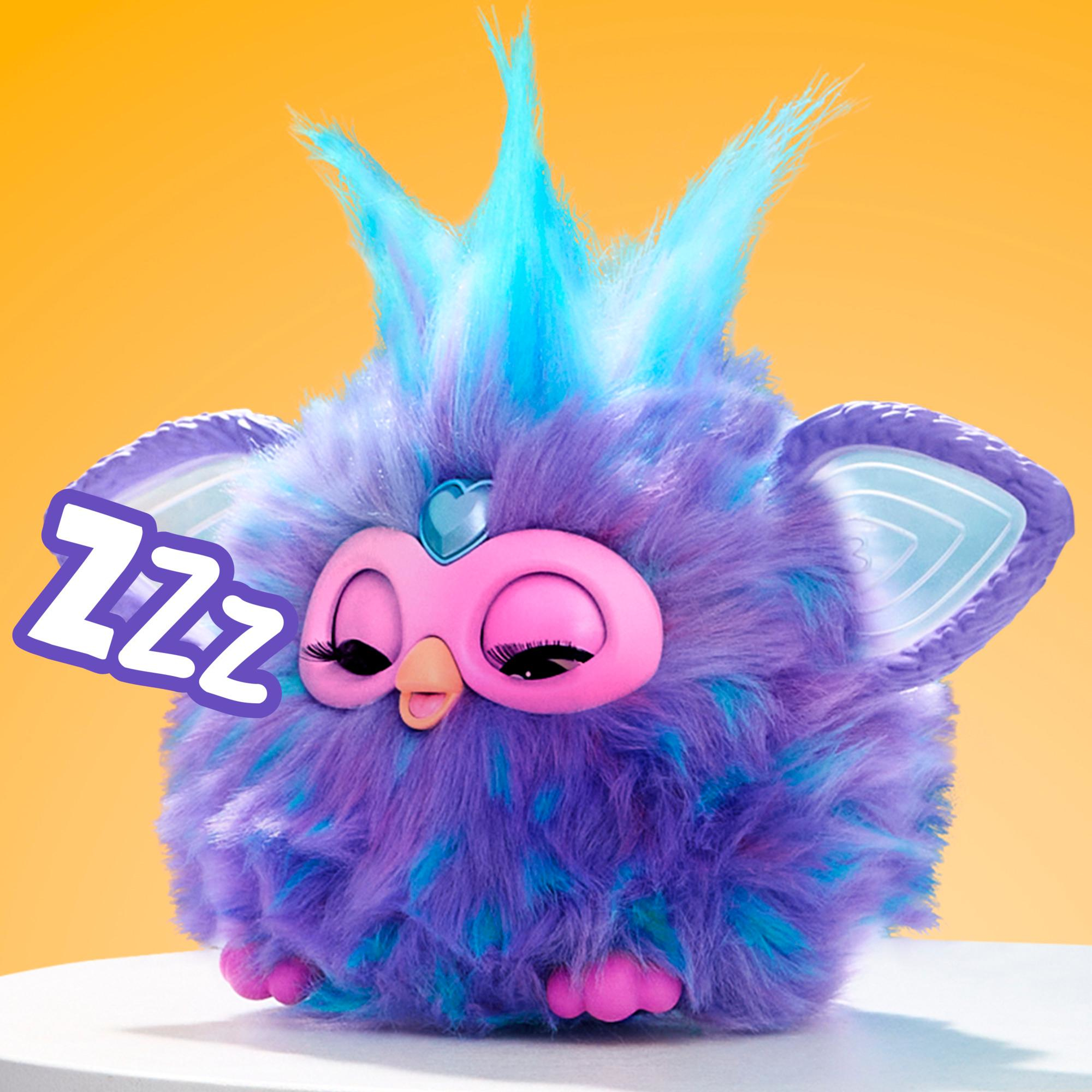 Ein schlafendes Furby-Spielzeug mit lila und blauem Fell, rosa Gesicht und dem Wort 'Zzz'. Gelber Hintergrund.