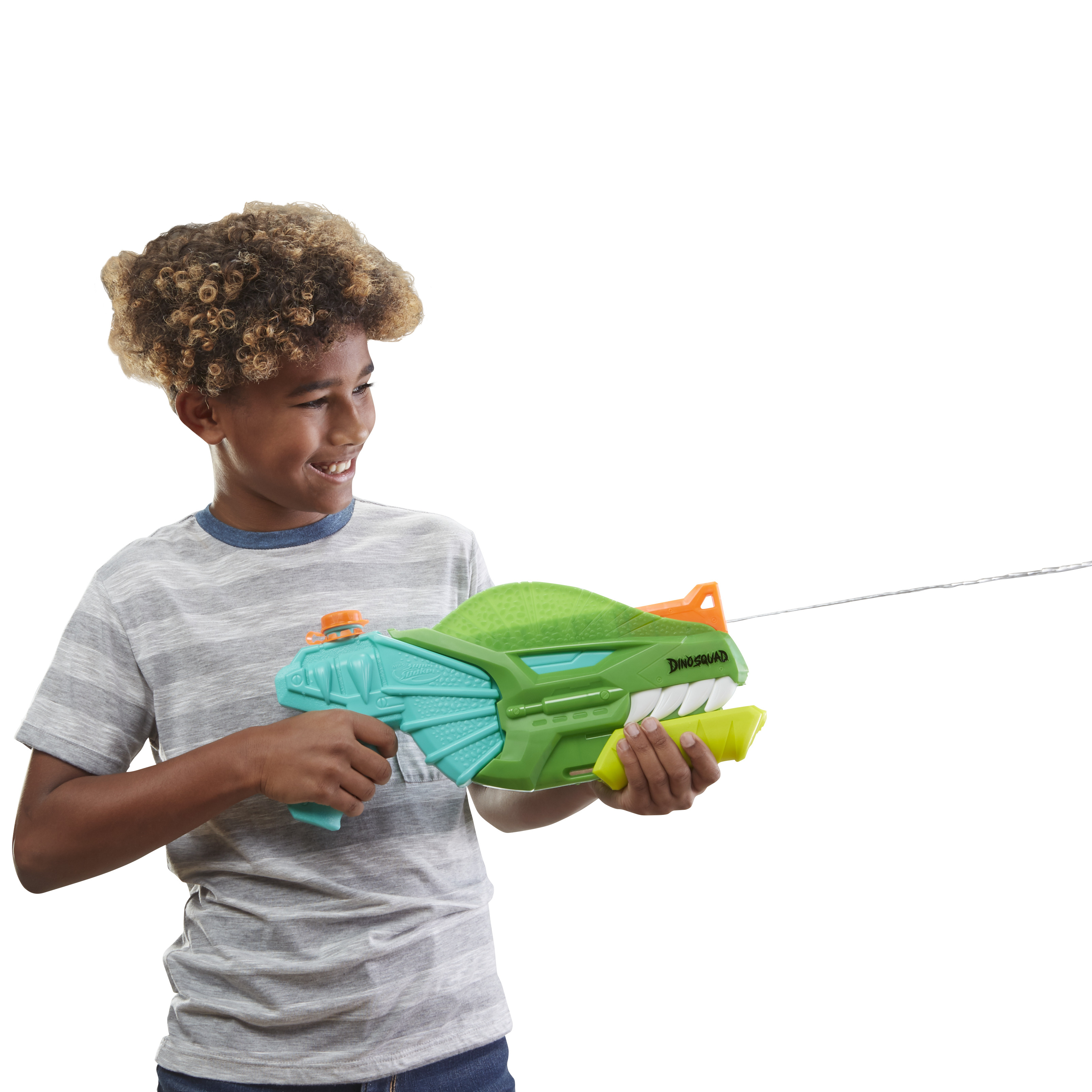 Un ragazzo sorride tenendo una pistola ad acqua a forma di dinosauro verde e turchese. L'acqua spruzza.
