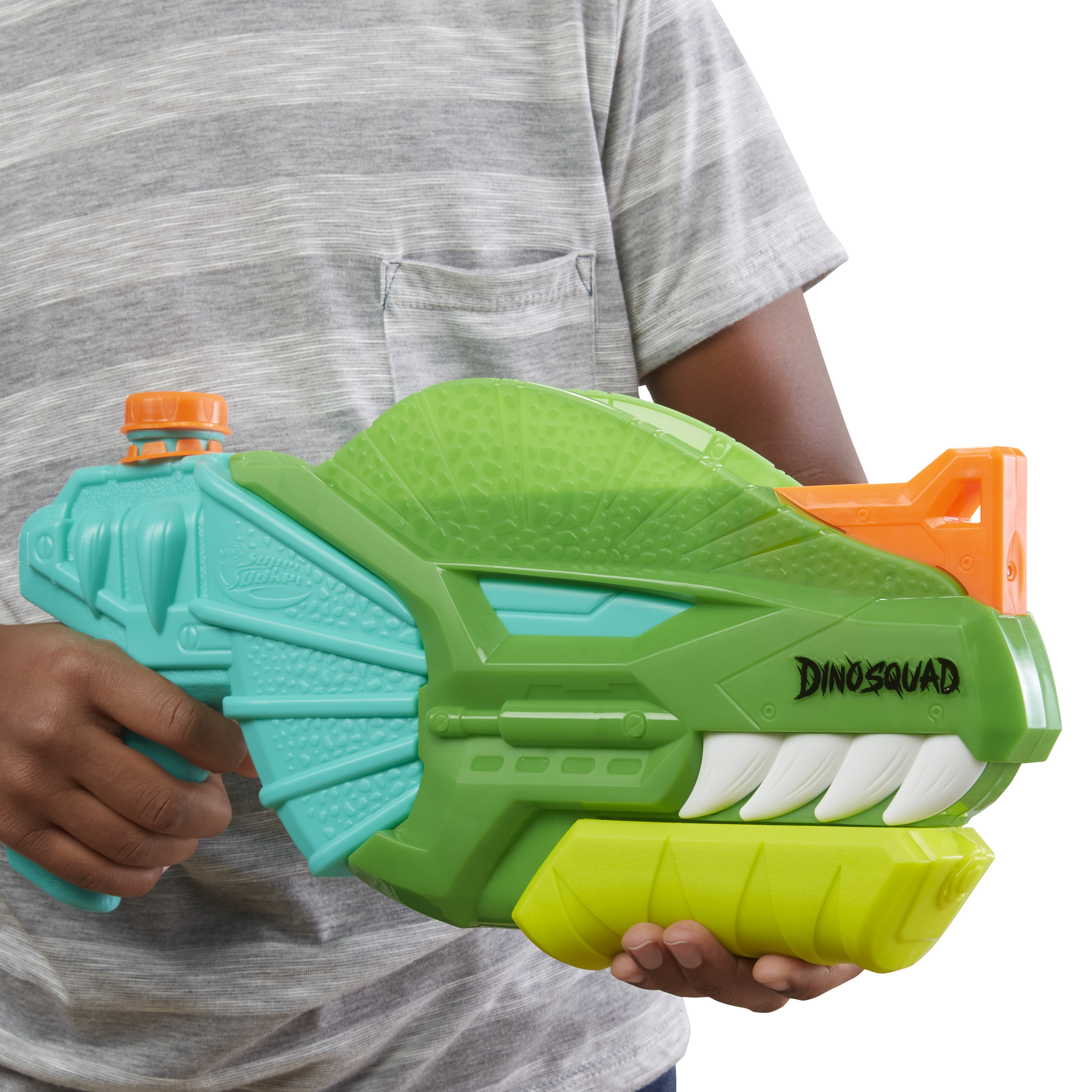 Una persona tiene in mano una pistola ad acqua a forma di dinosauro verde e arancione. La persona indossa una maglietta grigia a righe. Lo sfondo è bianco.