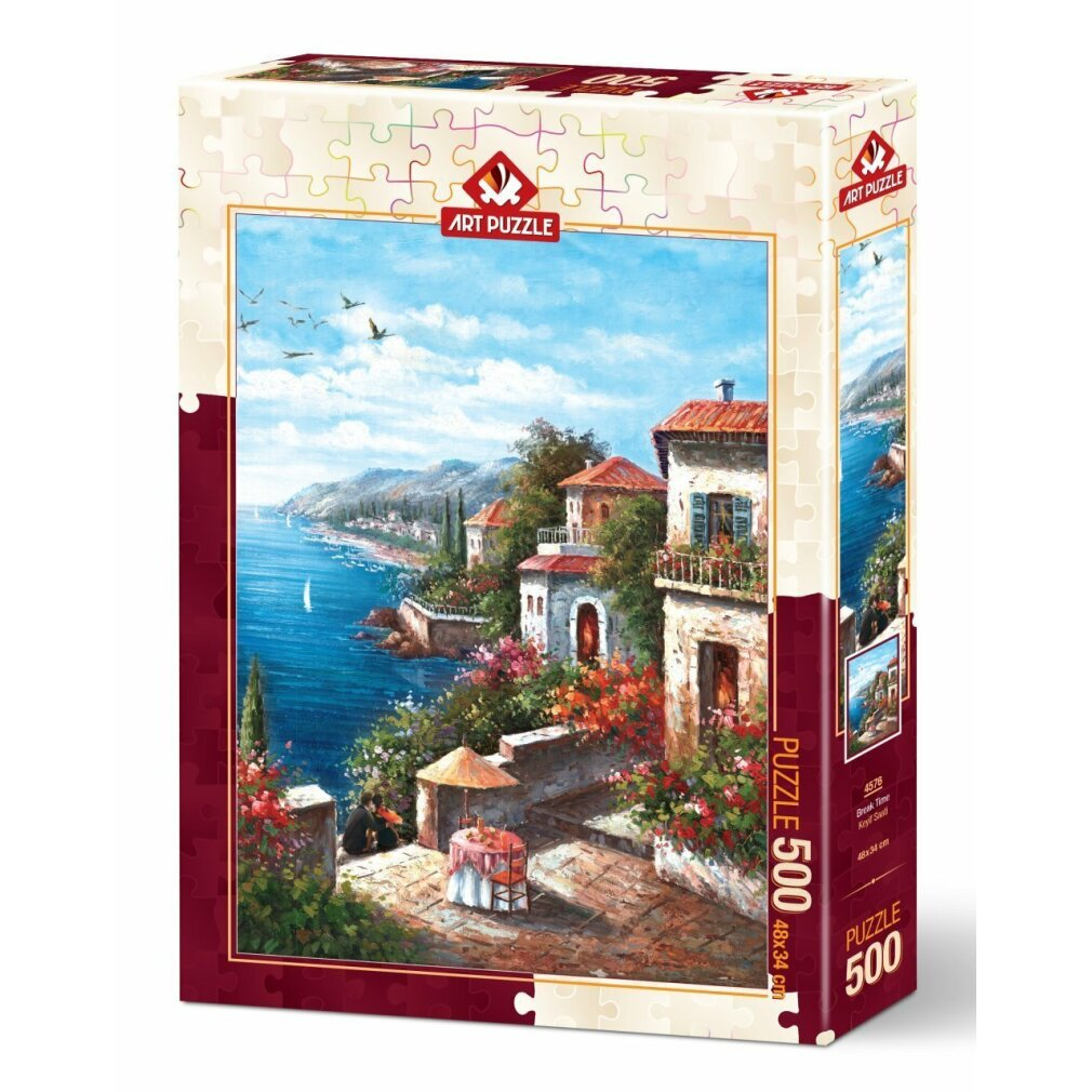 Puzzle kutusu, sahil köyü sahnesini gösteriyor. Kırmızı çatılı evler, mavi denize bakıyor. Teras üzerinde masa, kuşlar uçuyor.