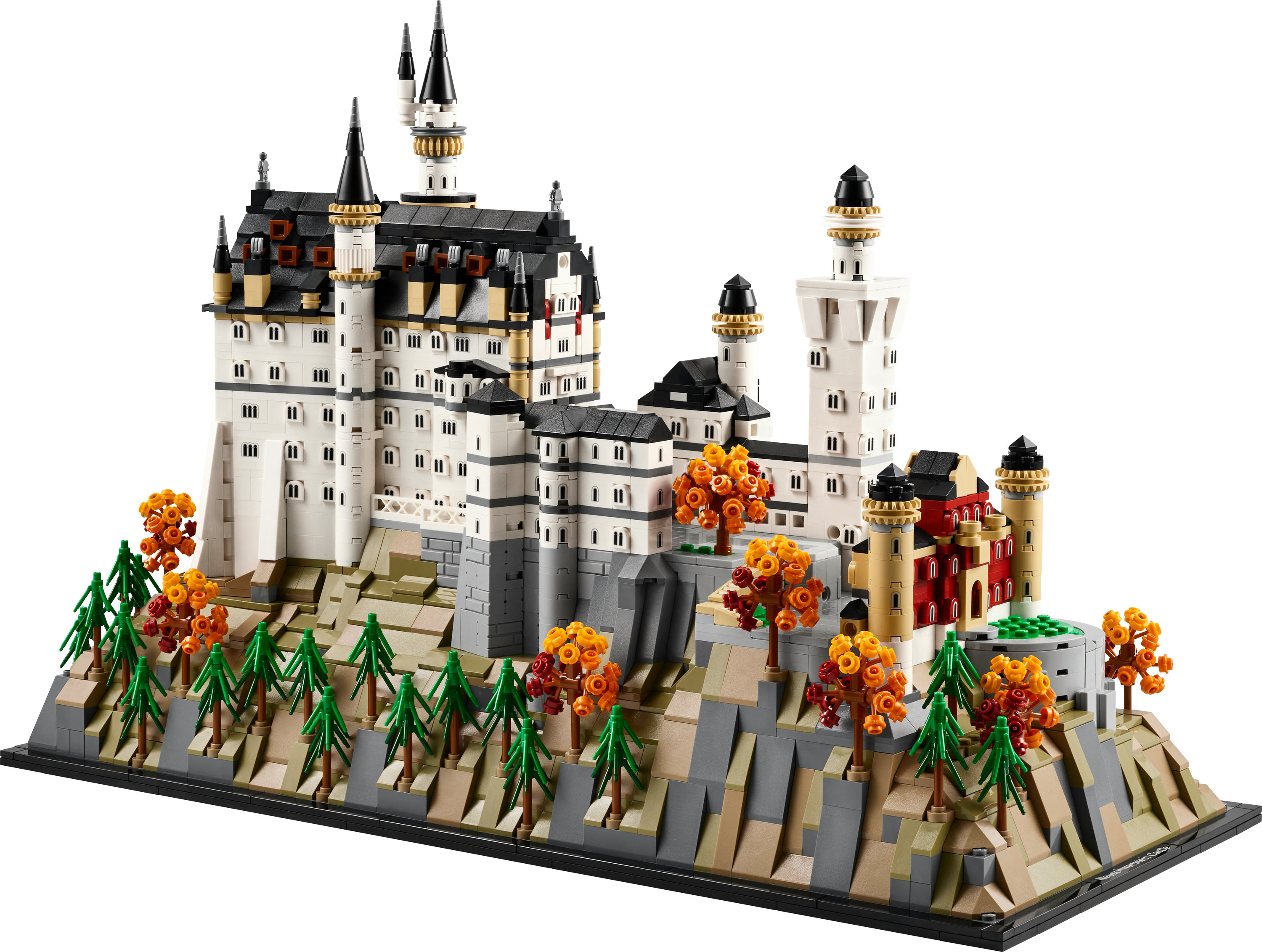 Model Lego zamku Neuschwanstein. Ma białe ściany, czarne dachy i wieże. Zielone drzewa i pomarańczowe liście.