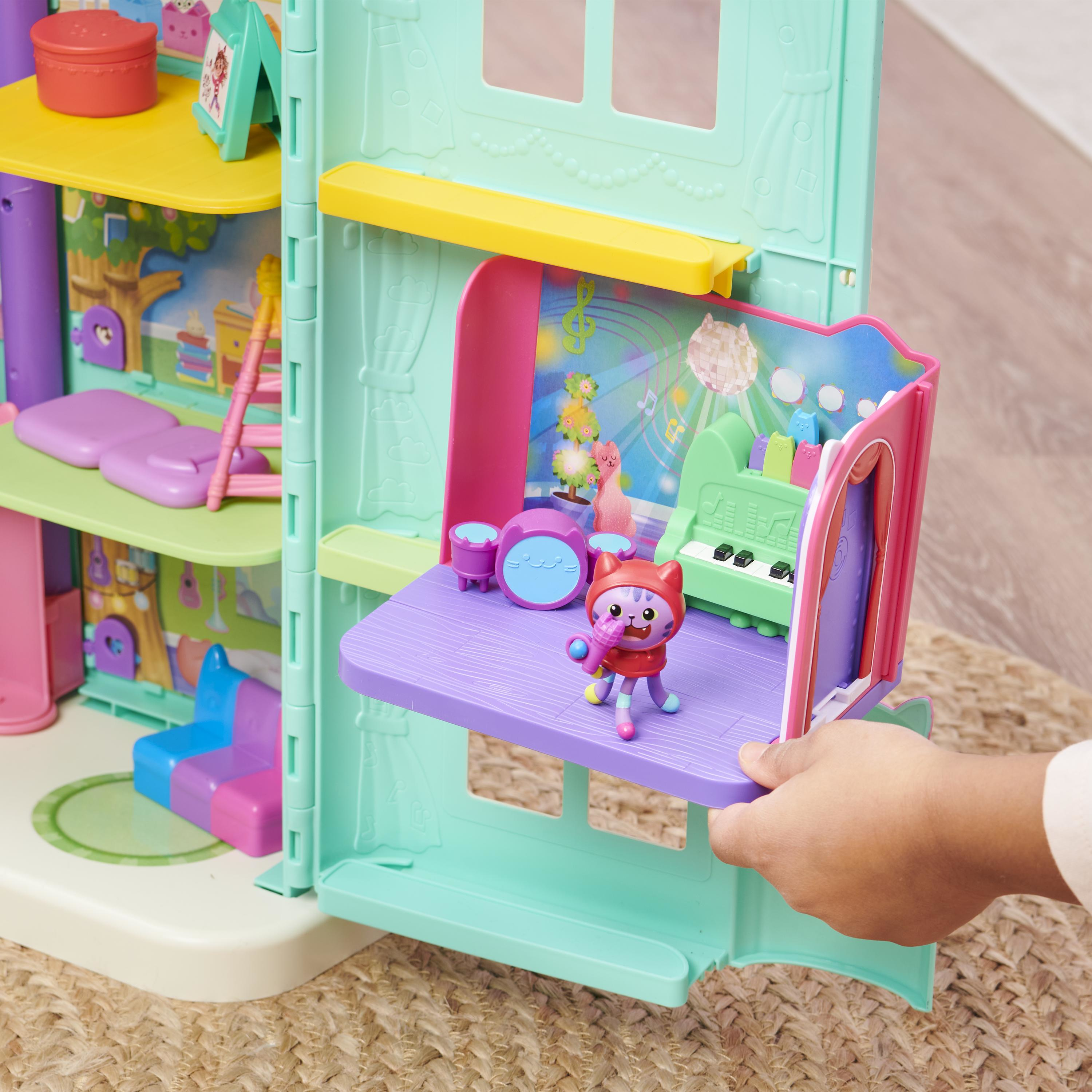 Zestaw do zabawy przedstawia scenę z figurką kota trzymającego mikrofon, zestawem perkusyjnym, fortepianem i ręką dziecka.