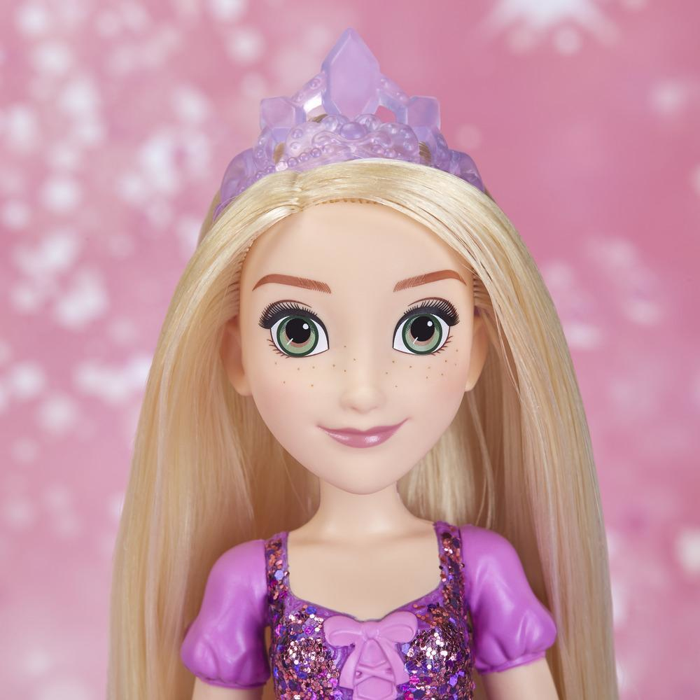 Una bambola di Rapunzel con lunghi capelli biondi, una corona viola e un vestito viola. Lo sfondo è rosa.