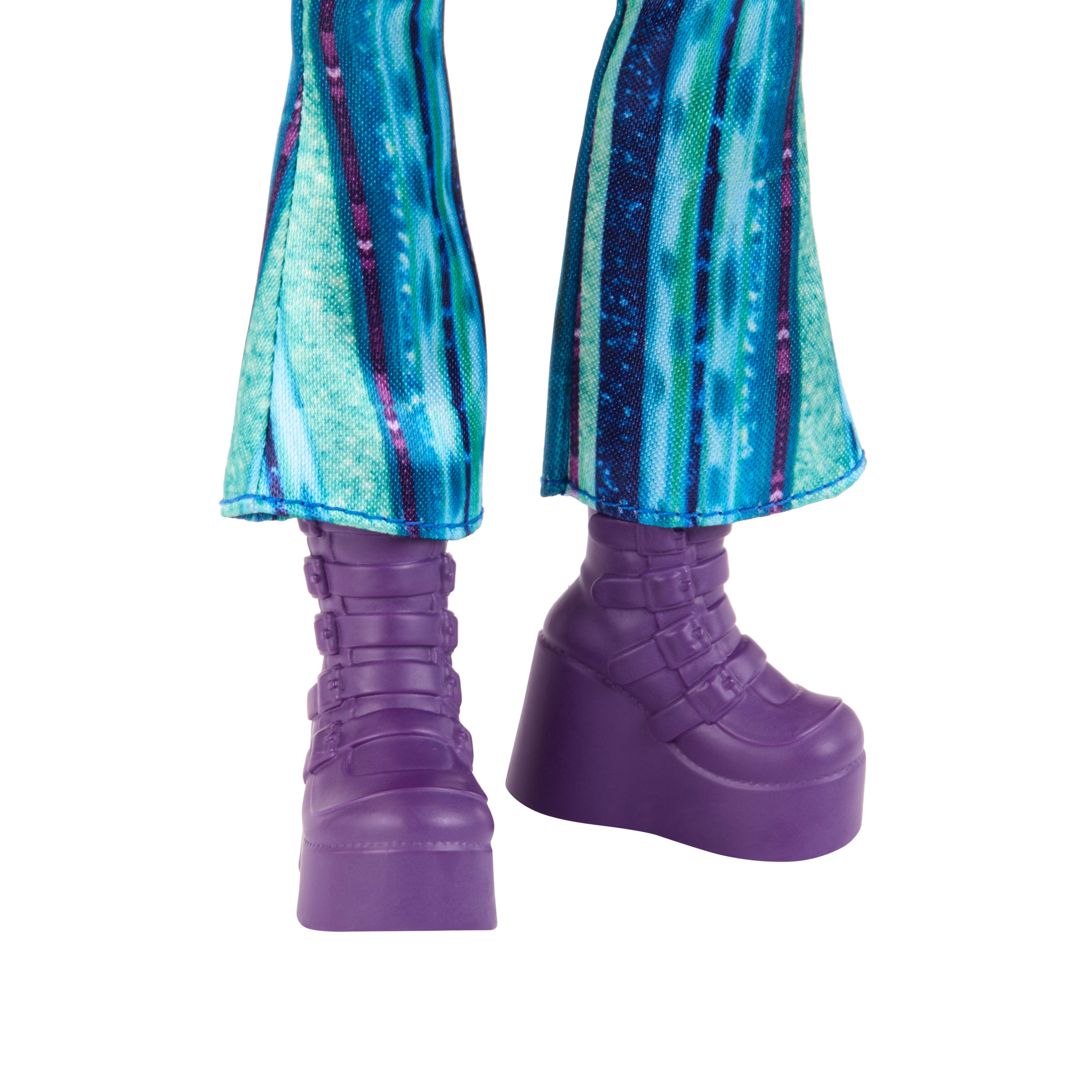 Nogi lalki w niebieskich spodniach we wzory i fioletowych butach na platformie na białym tle.