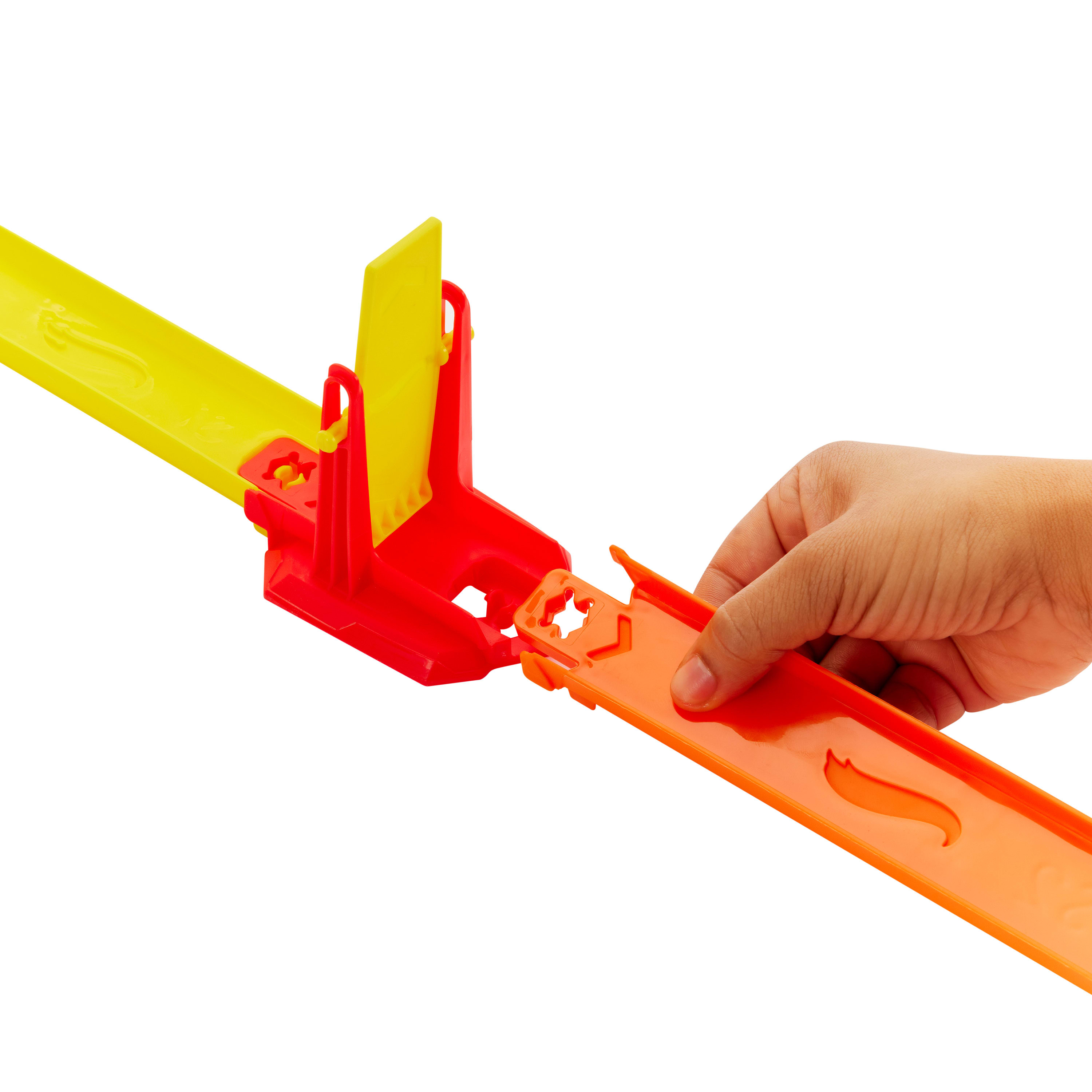 Dłoń łączy pomarańczowe i żółte elementy toru Hot Wheels. Widoczne są również czerwone konstrukcje wsporcze.