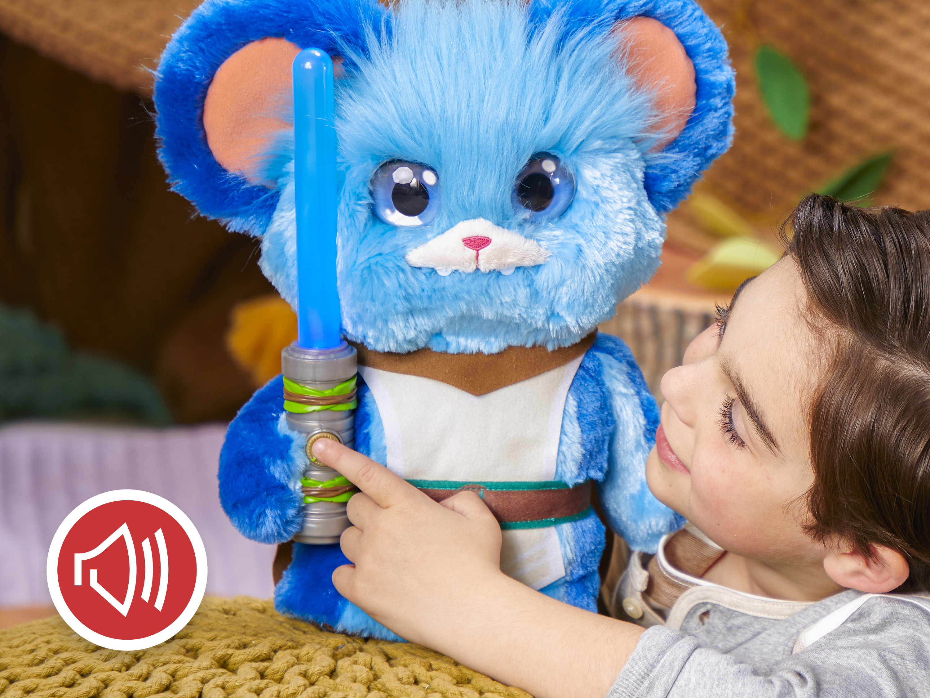 Dziecko naciska przycisk na niebieskiej pluszowej zabawce trzymającej niebieski miecz świetlny.
