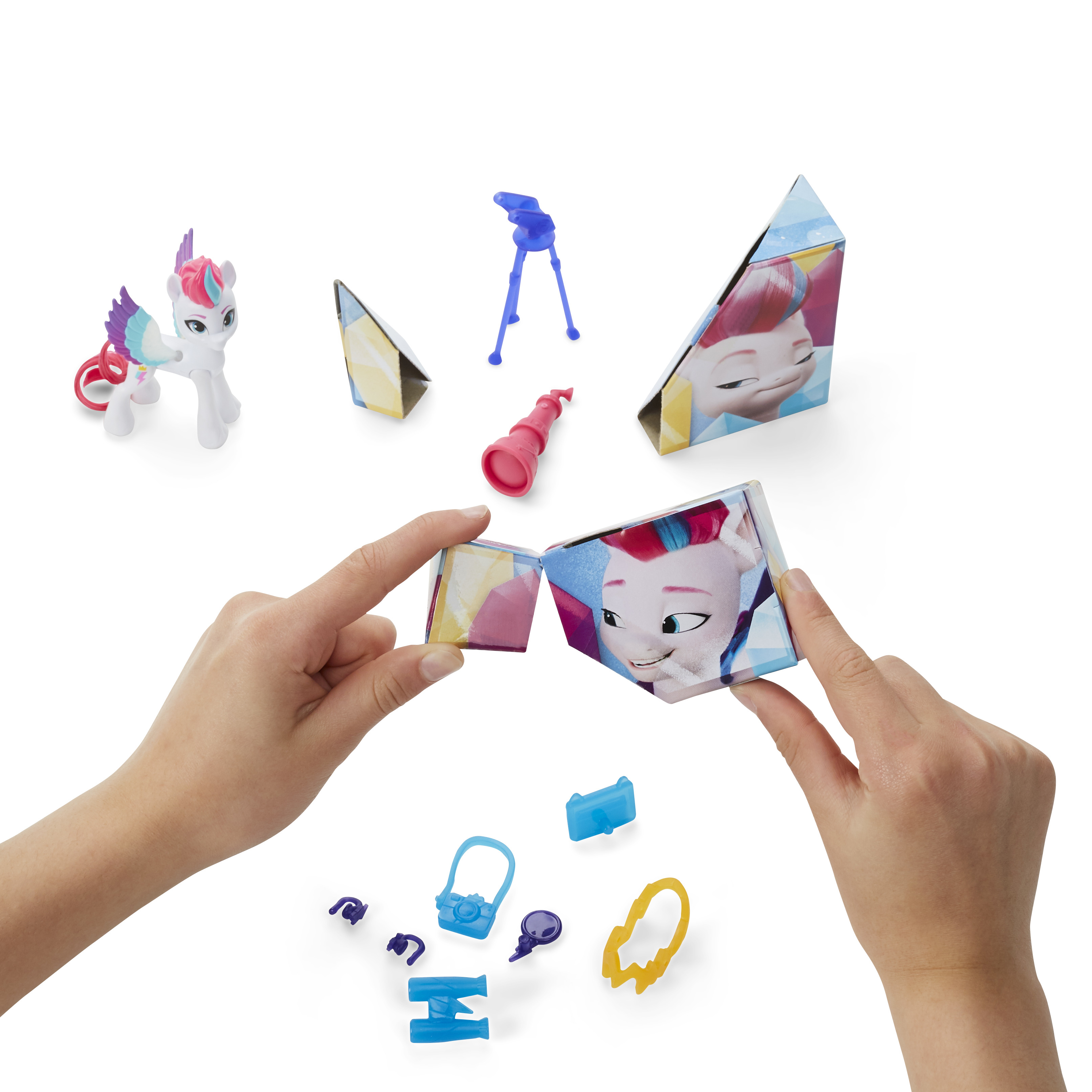 Zestaw zabawek z figurką kucyka, akcesoriami i dłońmi trzymającymi kostkę z twarzą kucyka.