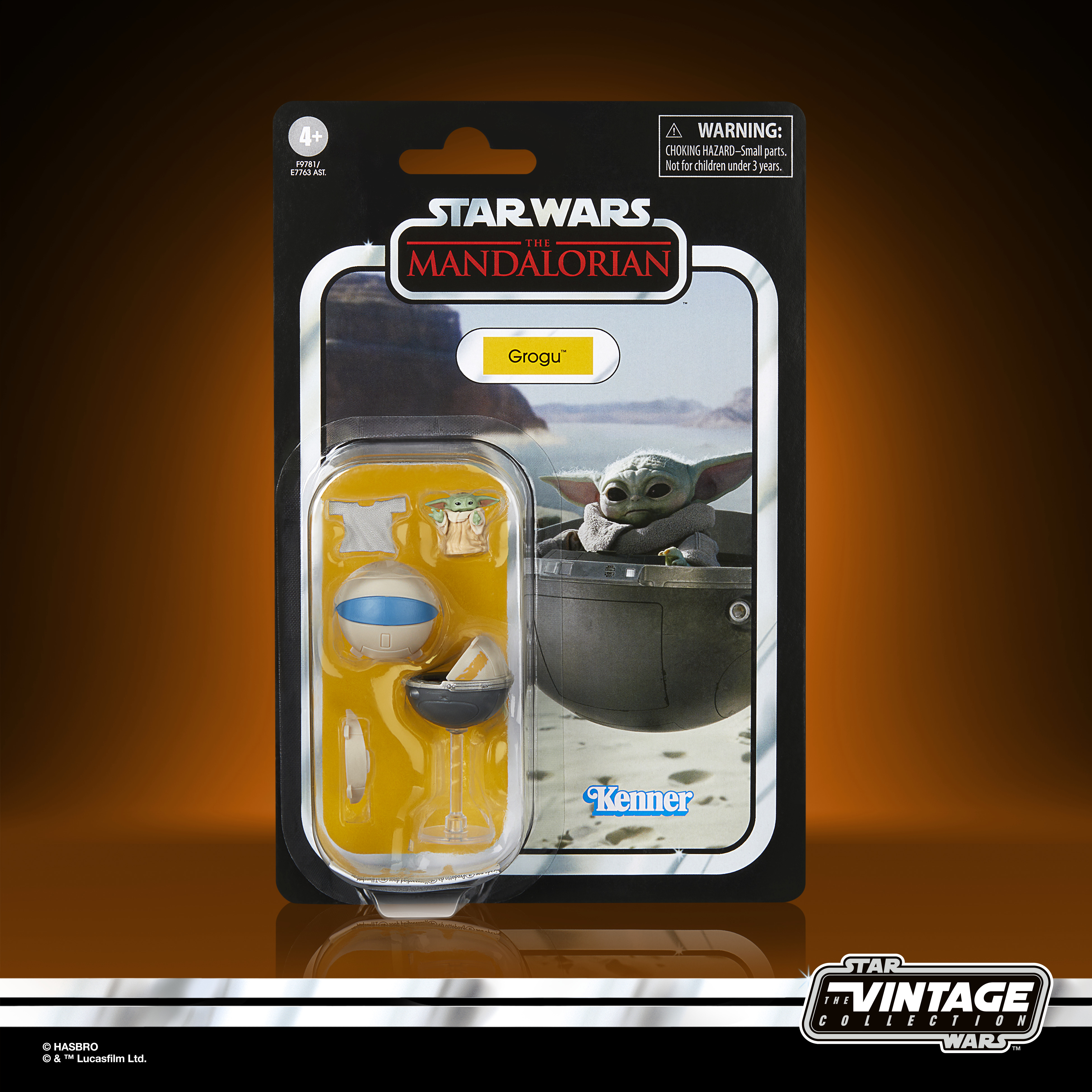 Ambalajında Star Wars Grogu aksiyon figürü. Ambalaj Grogu ve aksesuarları gösteriyor. Arka plan turuncu.