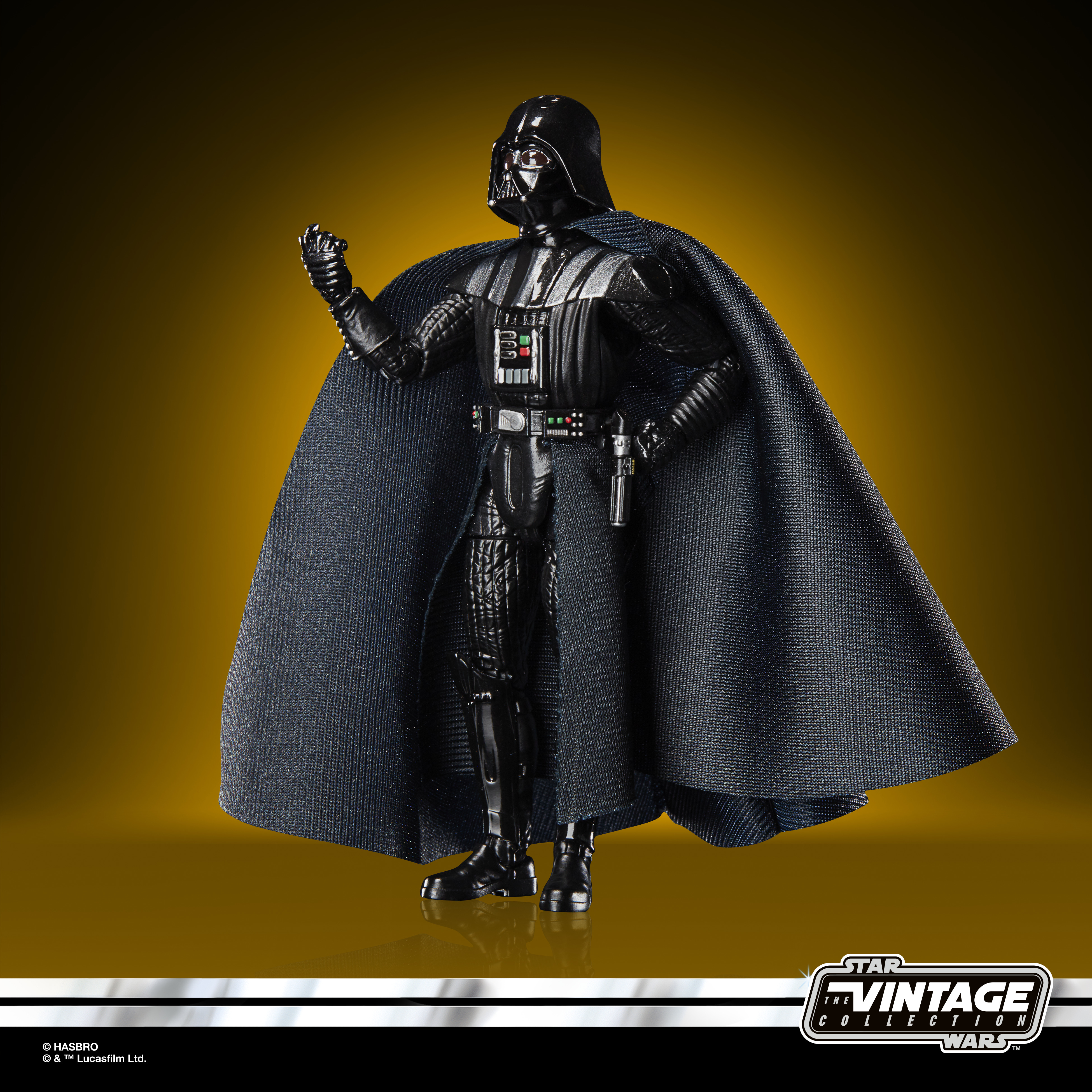 Action figure di Darth Vader con mantello. Elmo e armatura neri, spada laser sulla cintura. Sfondo oro e nero.