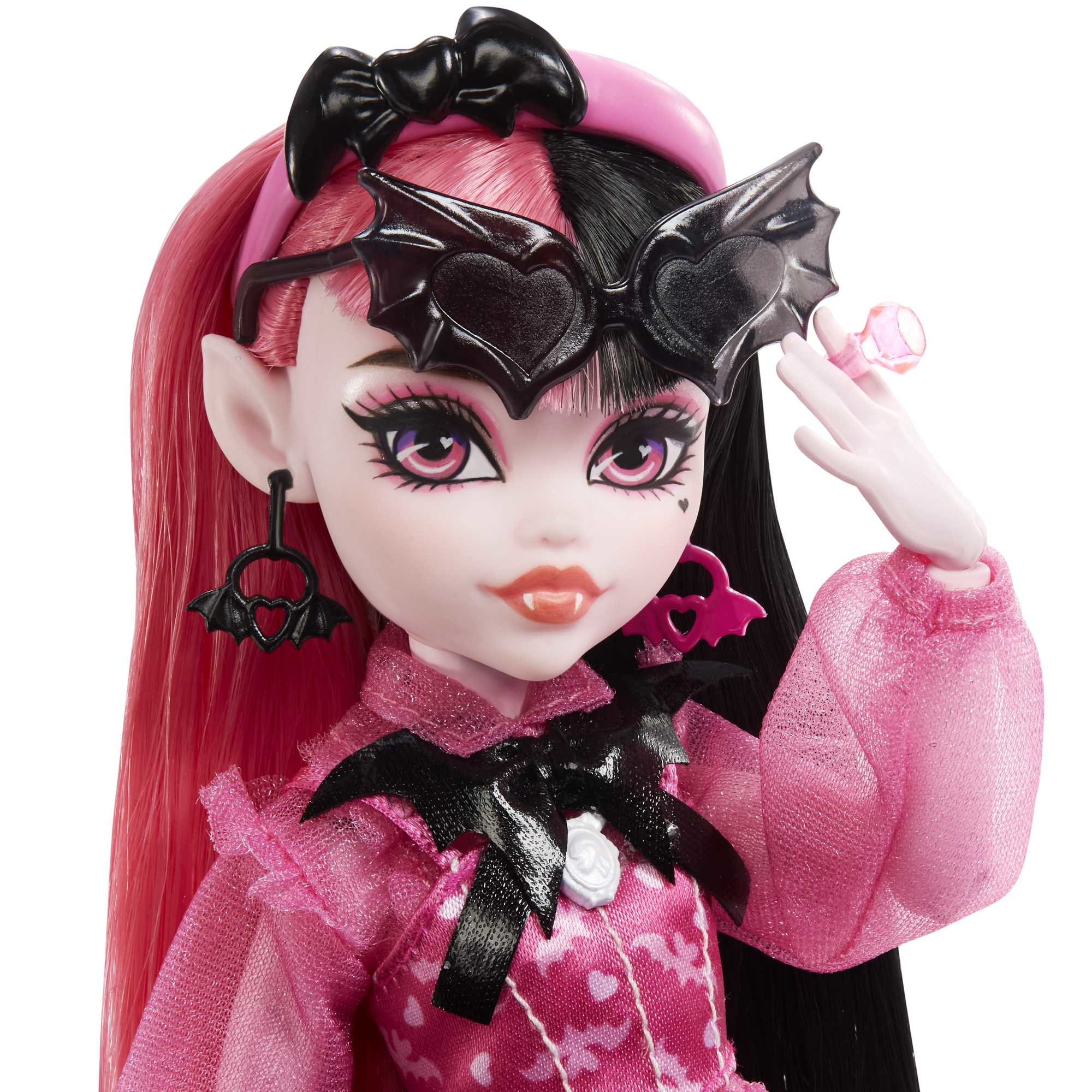 Puppe mit rosa und schwarzem Haar, trägt ein rosa Kleid, fledermausförmiges Zubehör und hält einen rosa Ring.