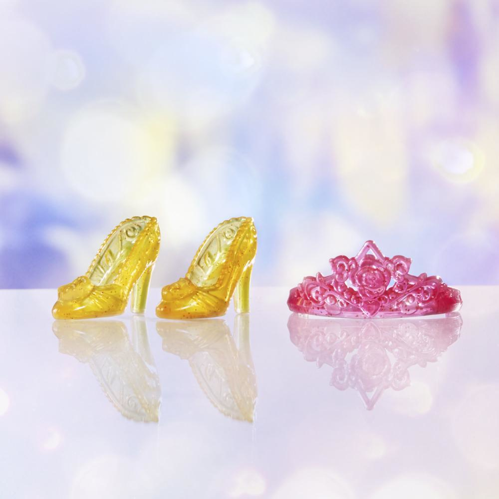 Due tacchi alti gialli e una tiara rosa su una superficie riflettente. Lo sfondo è sfocato bianco e blu.