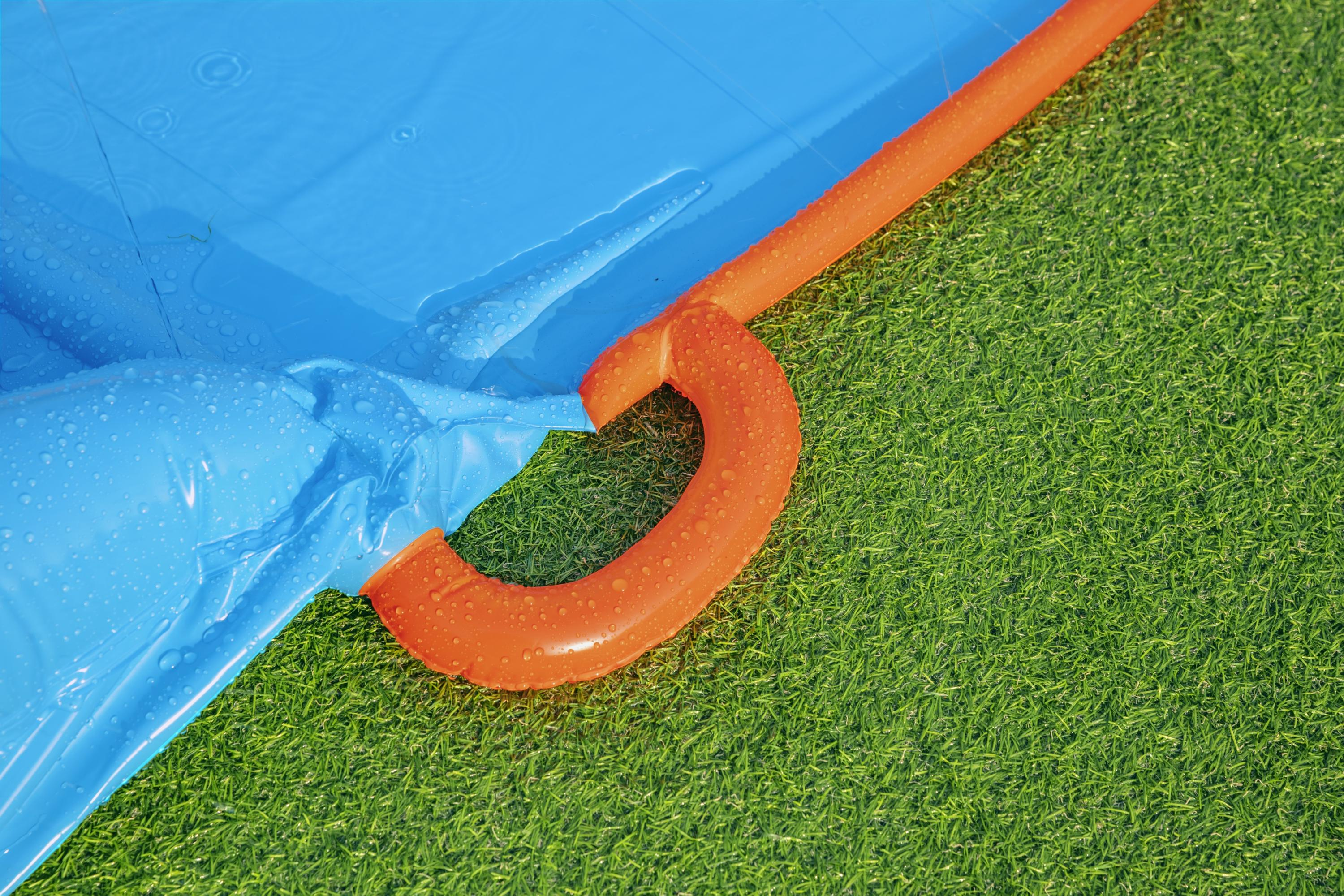 Niebieska nadmuchiwana zjeżdżalnia wodna z pomarańczowym uchwytem spoczywa na zielonej sztucznej trawie.