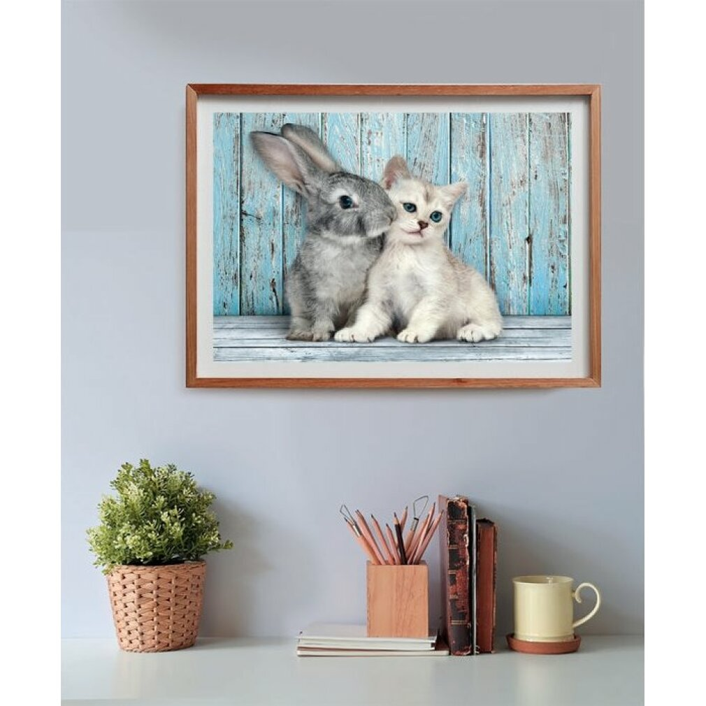 Une image encadrée d'un lapin et d'un chaton qui s'enlacent est sur une étagère. Une plante, des crayons, des livres et une tasse sont également visibles.