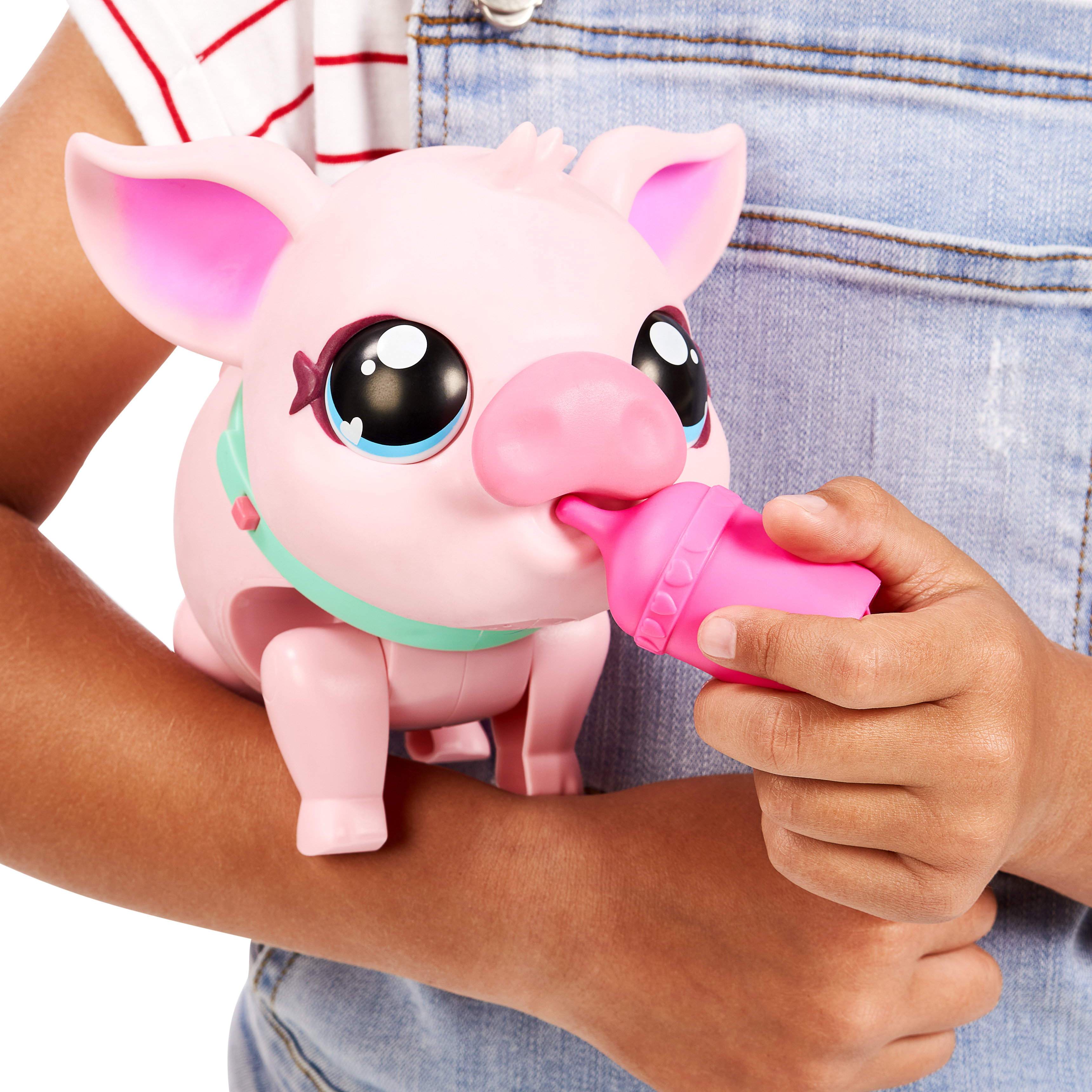 Ein rosa Spielzeugschwein, das von einer Person in einem Jeans-Outfit mit einer rosa Flasche gefüttert wird.