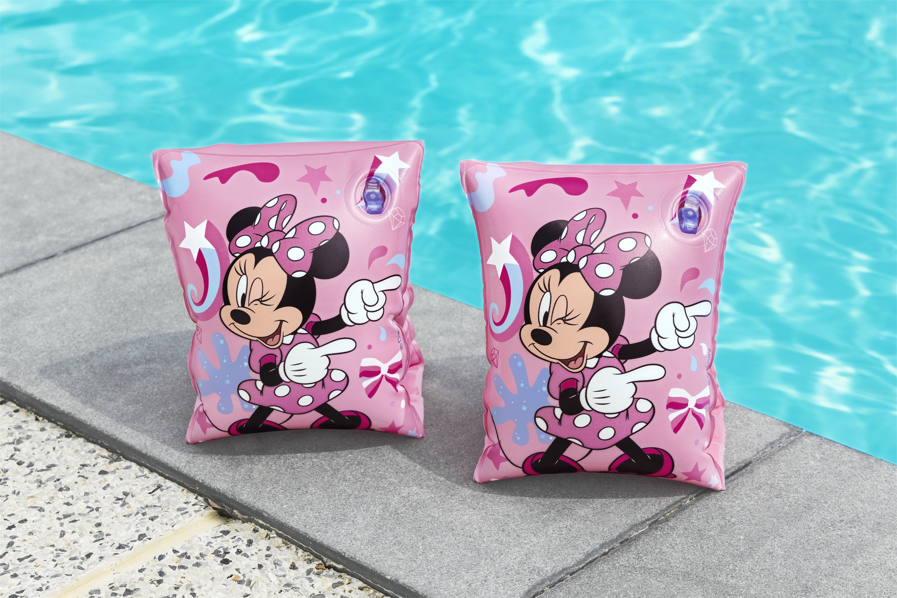 Dos flotadores rosas de Minnie Mouse sobre el borde de la piscina. El fondo es una piscina azul.