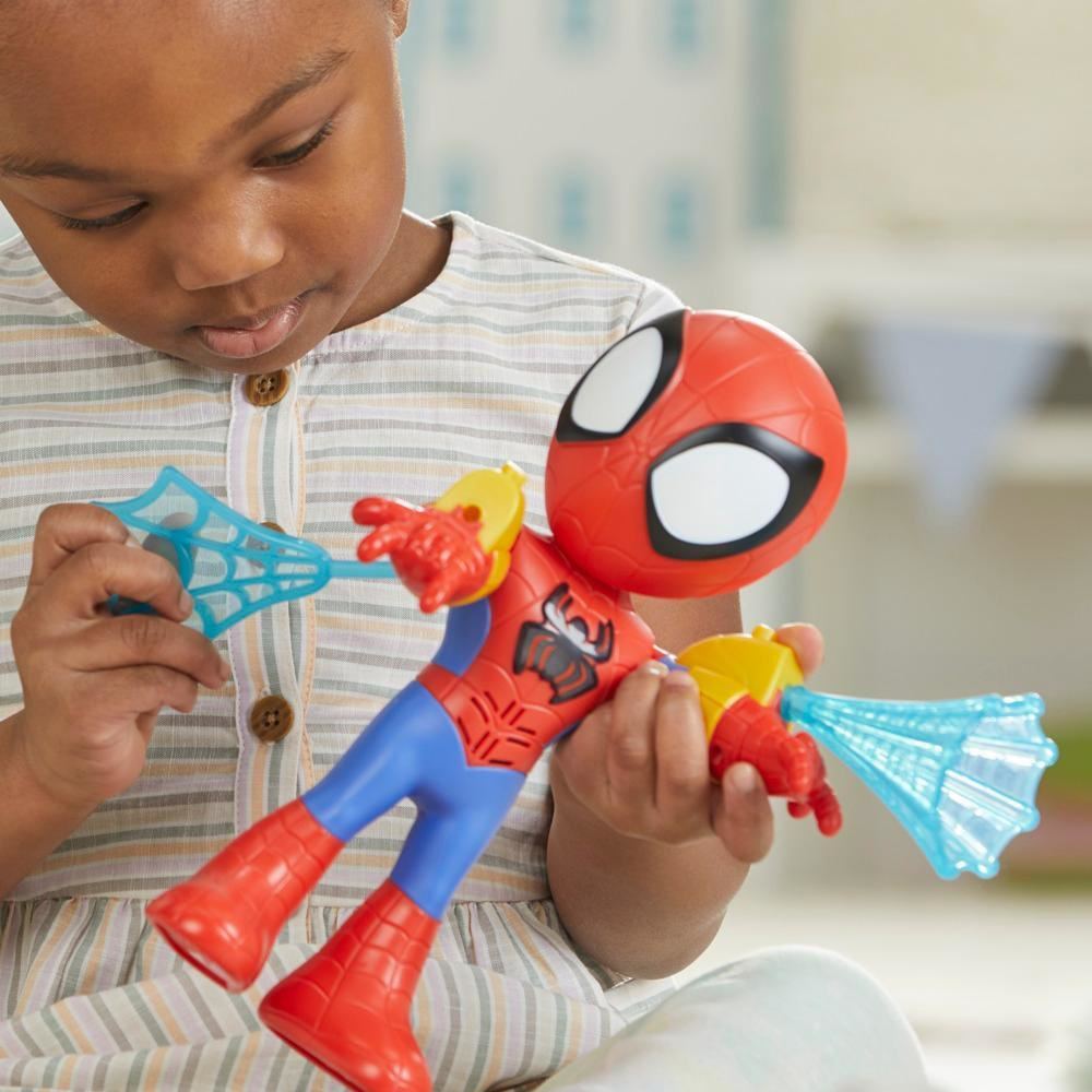 Un niño sostiene un juguete de Spider-Man. El juguete tiene una cabeza roja y un cuerpo azul y rojo. Una telaraña está en la mano izquierda.