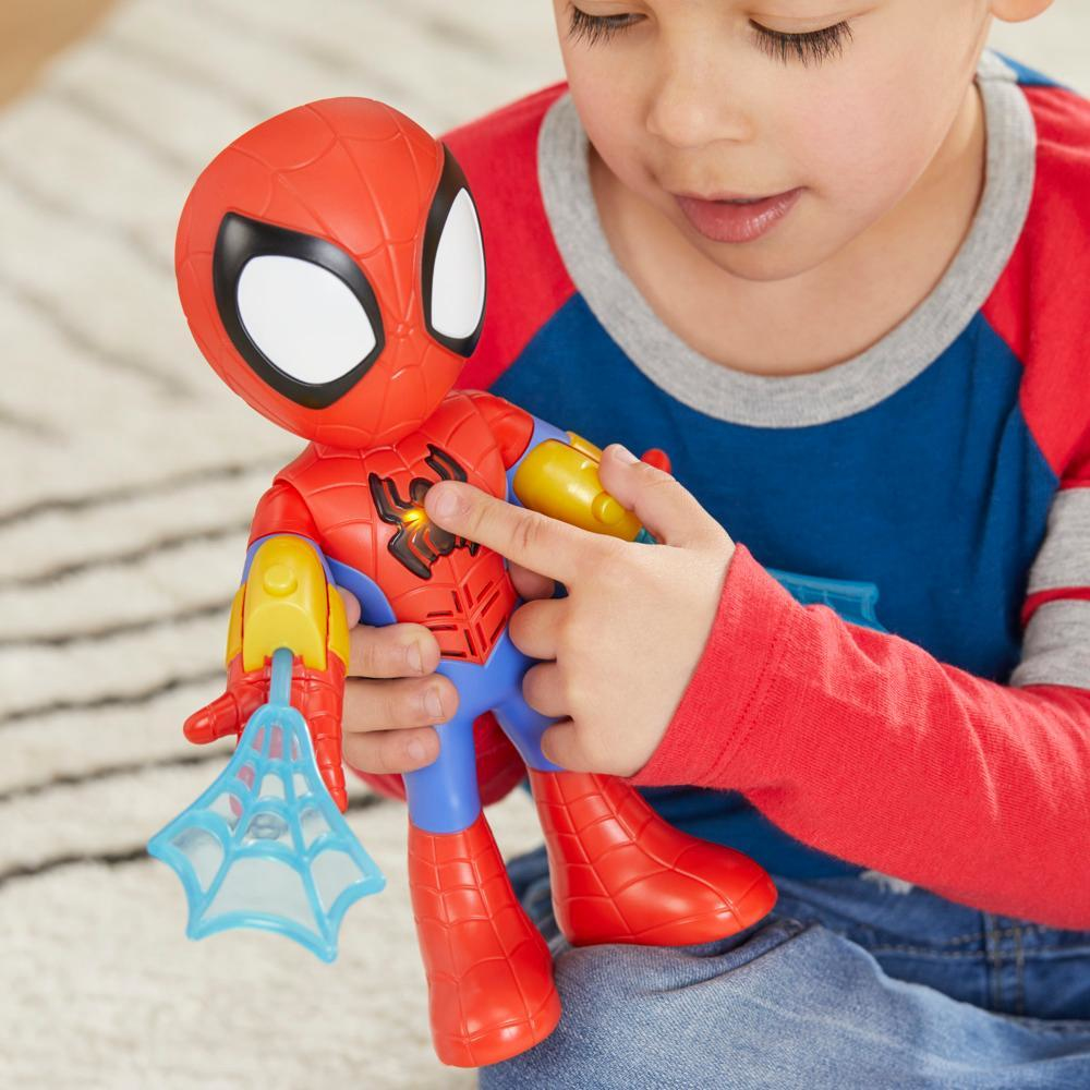 Un niño sostiene un juguete de Spider-Man. El juguete es rojo, azul y amarillo con un lanzador de telarañas. El niño lleva una camisa roja y azul.
