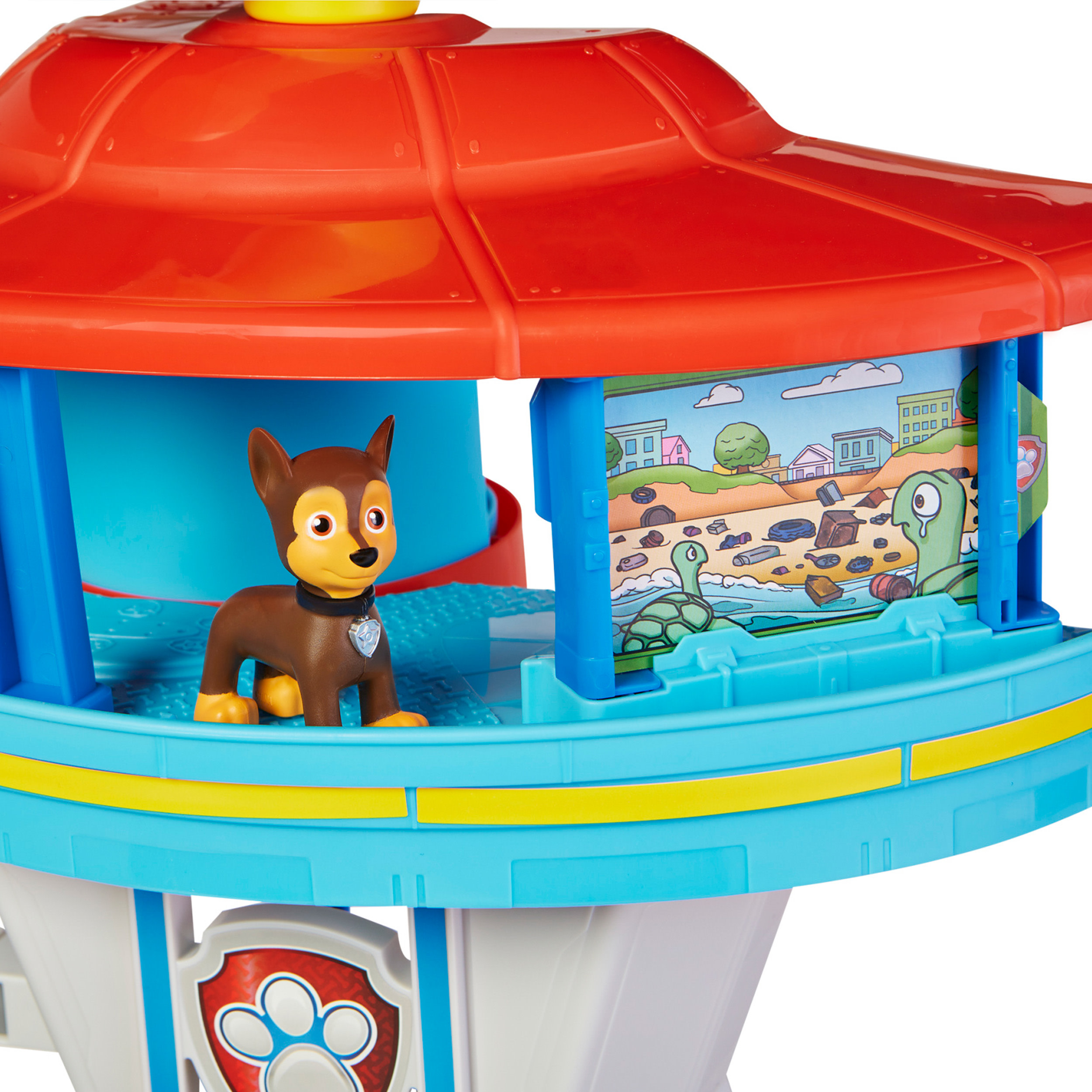 Una torre giocattolo di Paw Patrol con la figura di Chase. Ha un tetto rosso, una base blu e un'immagine di una spiaggia inquinata.