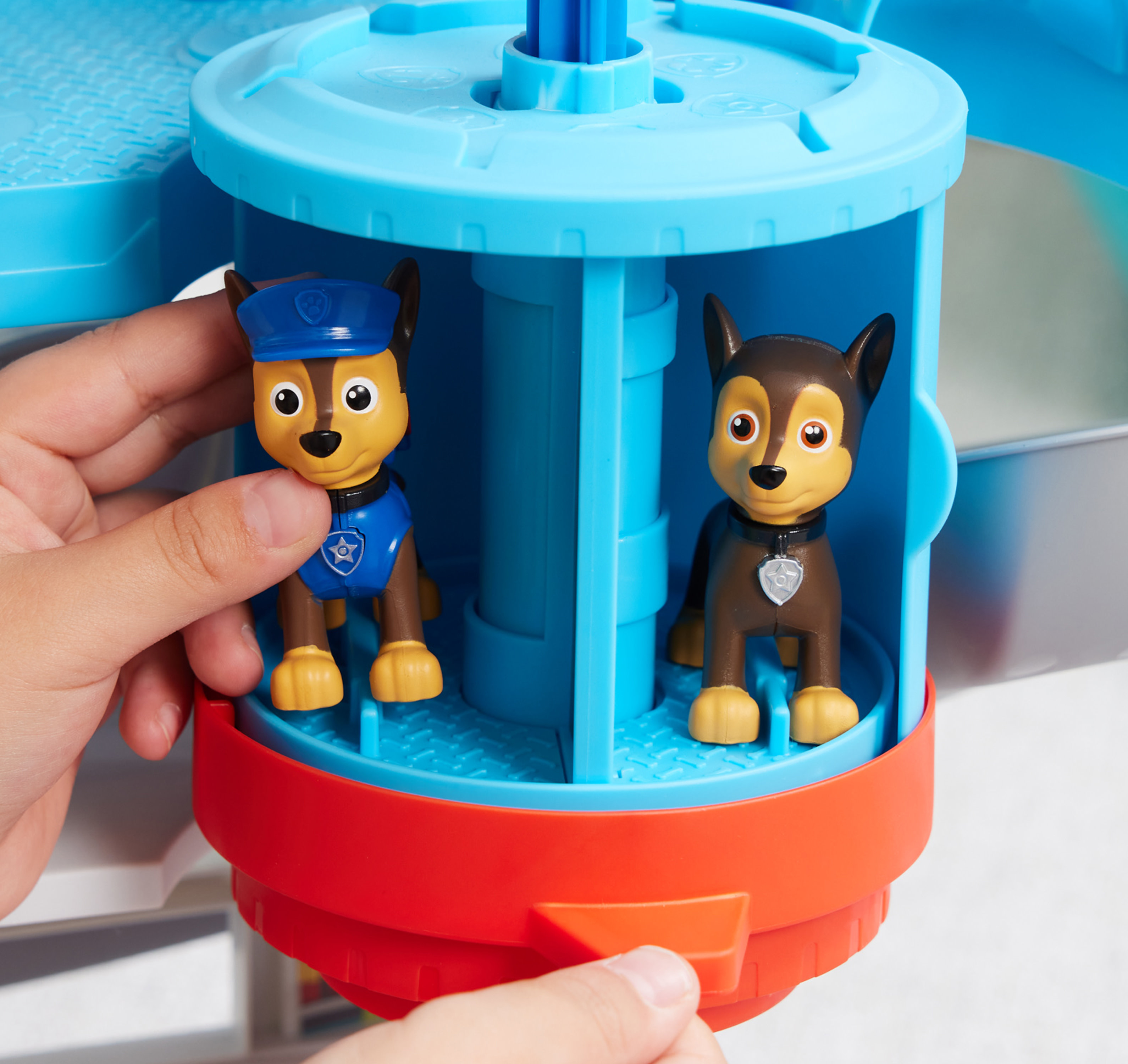 Mani che tengono cuccioli giocattolo. Un cucciolo indossa una divisa blu, l'altro marrone. Il giocattolo è blu e rosso.