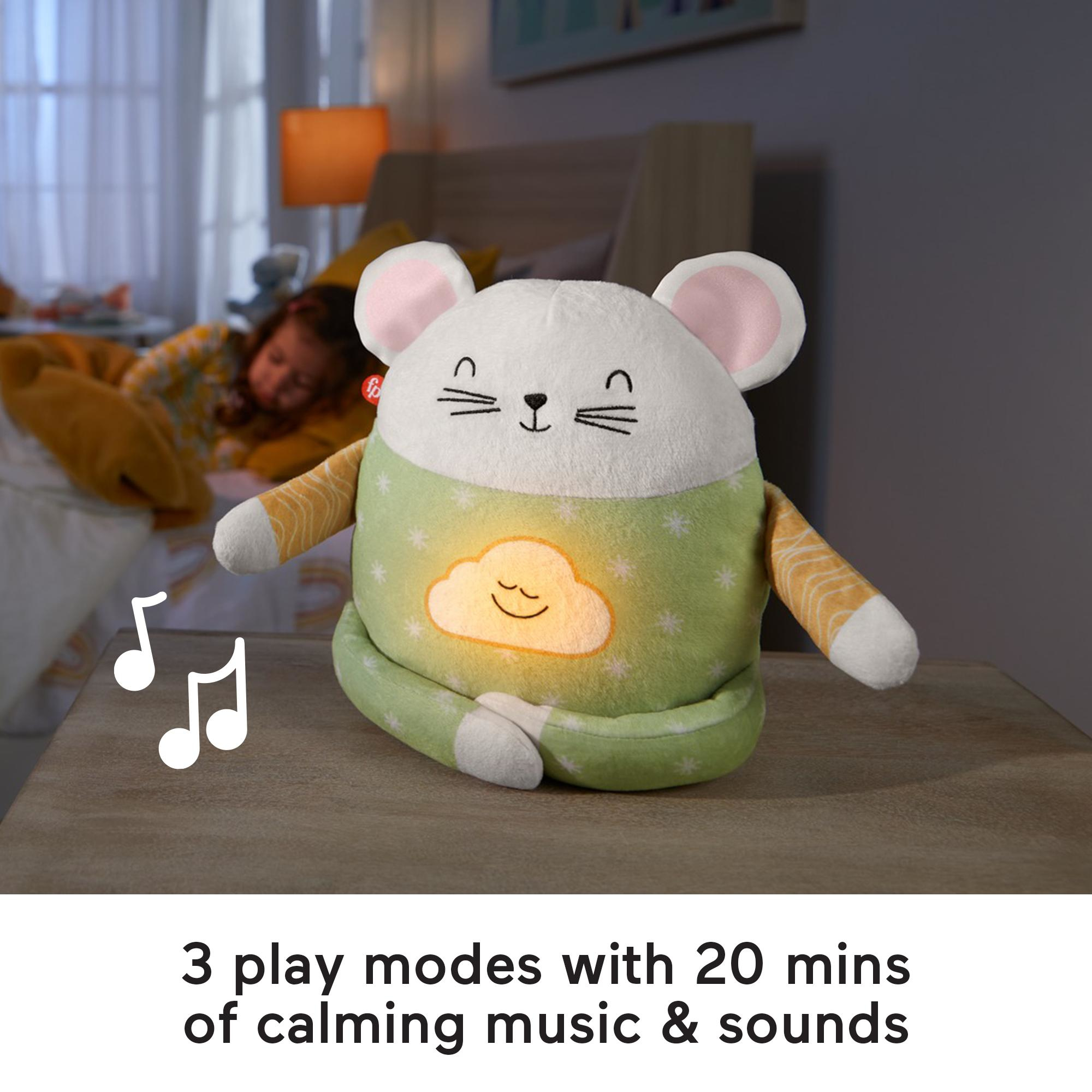 Biała pluszowa mysz z zielonym korpusem i śpiące dziecko w tle. Nuty muzyczne po lewej stronie.