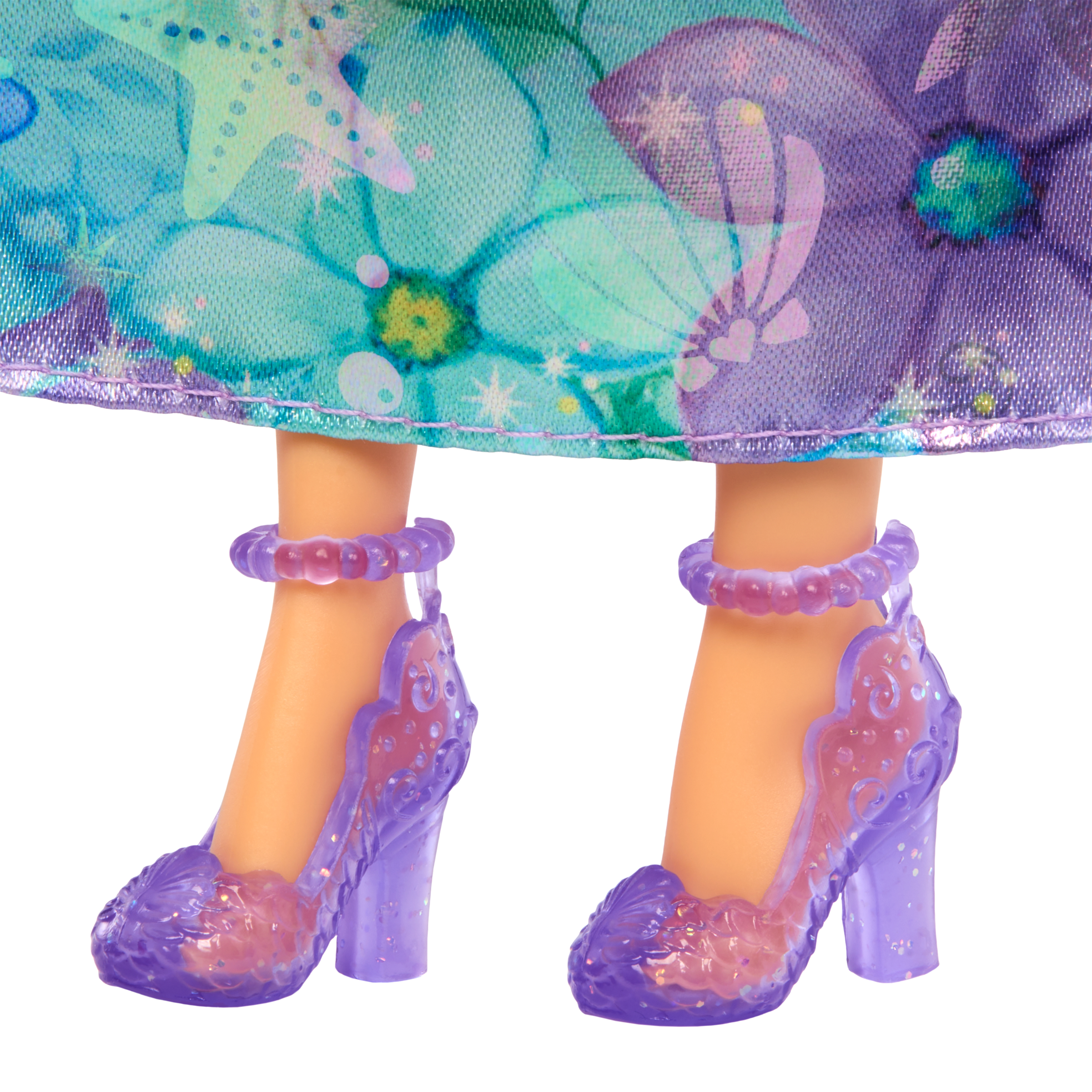 Nogi lalki z fioletowymi obcasami. Sukienka jest niebiesko-fioletowa we wzory kwiatowe. Buty mają brokat.