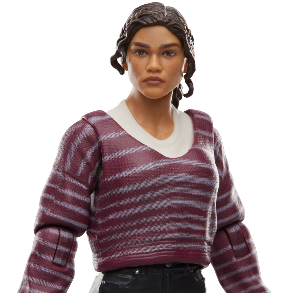 Figura kobiety o brązowej skórze i ciemnych włosach. Nosi czerwony sweter w paski na białej koszuli i czarnych spodniach.