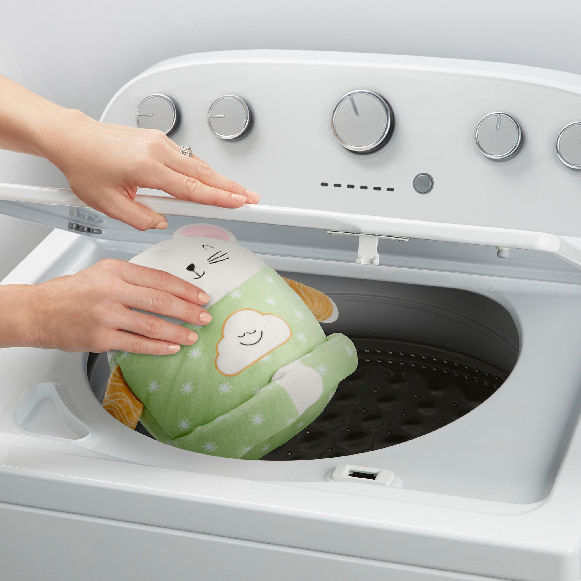 Osoba wkłada zieloną zabawkę do białej pralki. Zabawka ma króliczą buzię i wzór chmurki.