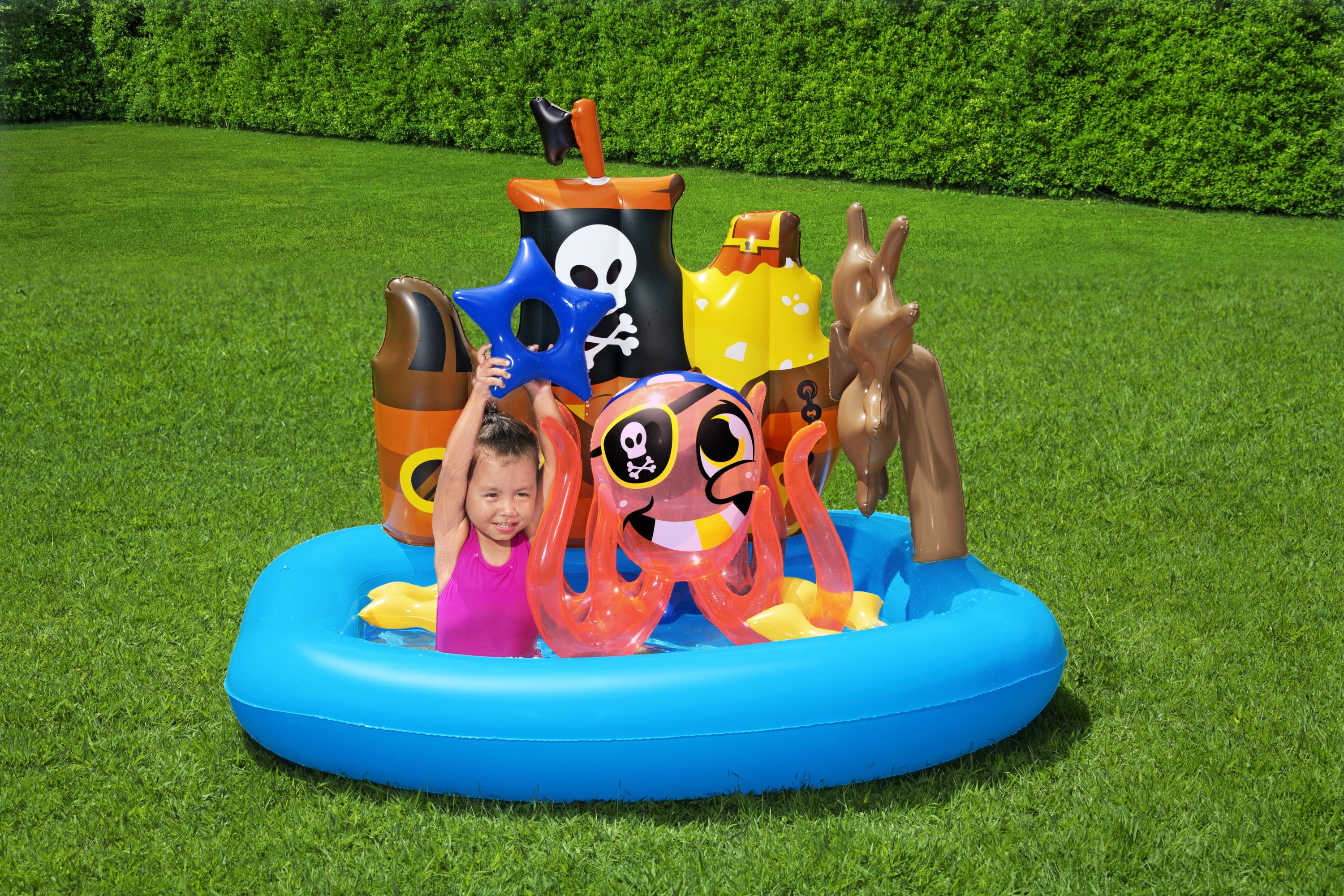 Ein Mädchen in einem rosa Badeanzug ist in einem blauen aufblasbaren Pool und hält einen blauen Stern mit Piratenschiff im Hintergrund.
